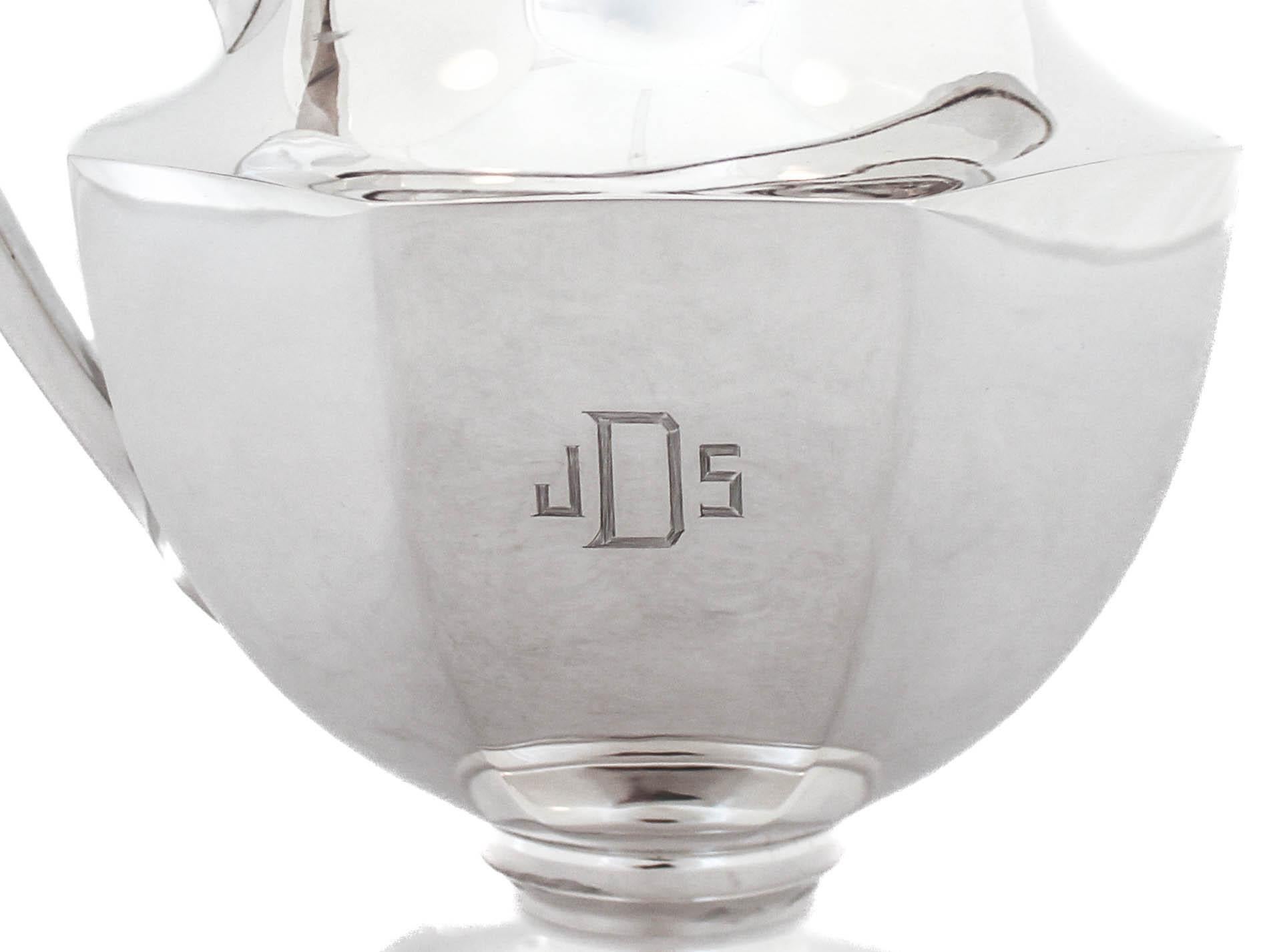 Se ofrece una jarra de agua de plata de ley de la Schofield Company de Baltimore, Maryland.  Conocida por sus diseños súper elegantes y modernos, esta jarra de agua es la quintaesencia de Schofield.  Tiene un cuerpo facetado con un mango angular. 