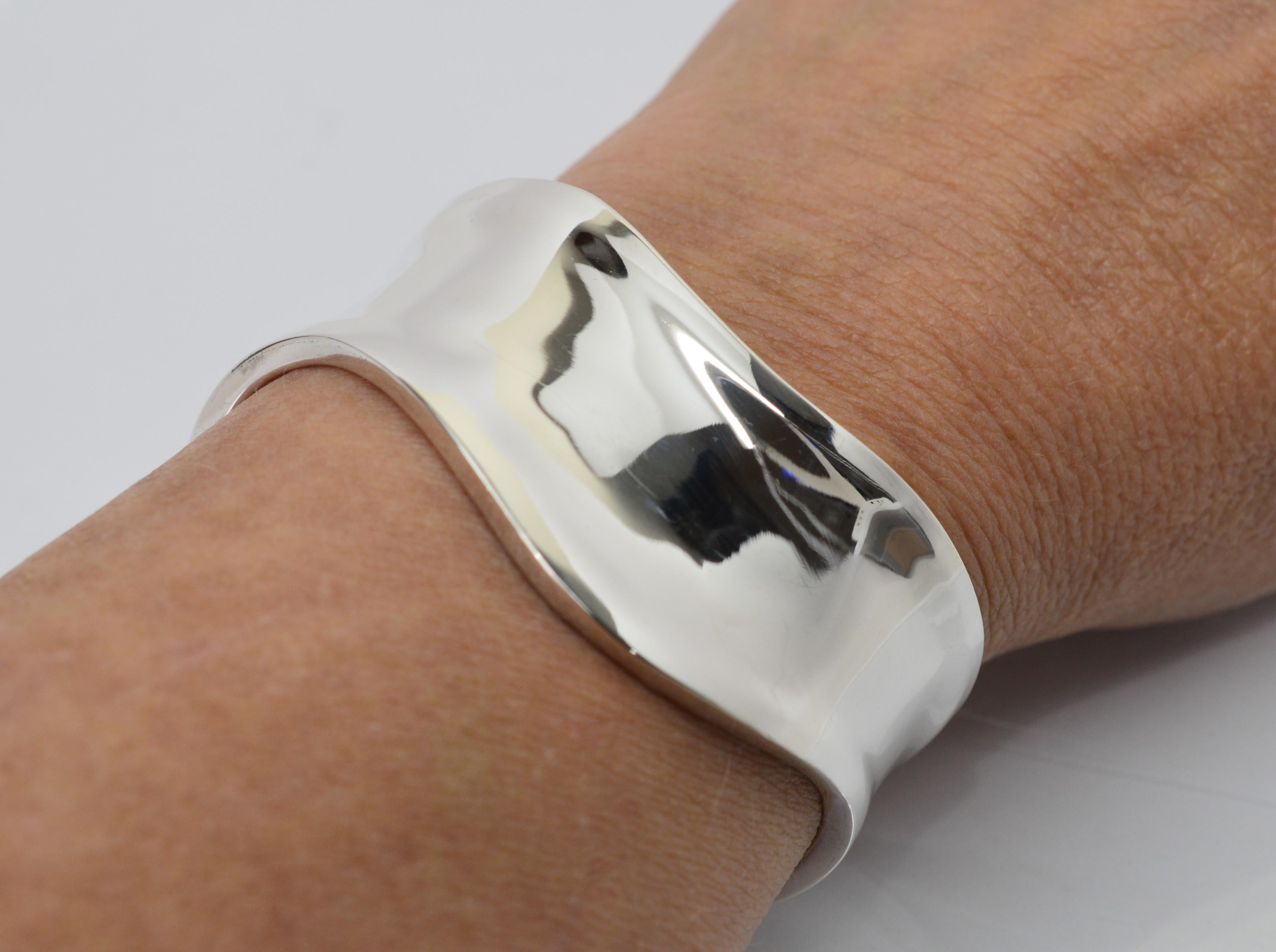 Like a wave of sterling silver flowing over the wrist, this 1 inch wide cuff bracelet makes a modern statement. The cuff measures 5-1/2 inch around plus has a 1-1/4 inch opening for a total inside measurement of 6-3/4 inches. Nicely polished,