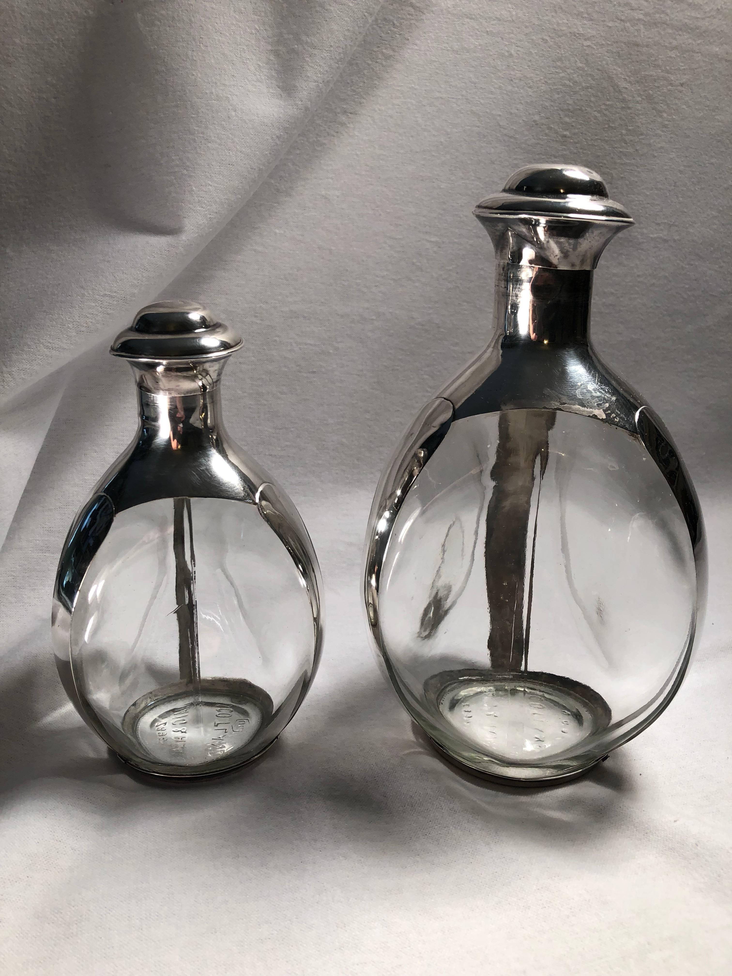 Elegant but simple in design these beautiful scotch whisky decanters are somewhat rare in that they are a set of two. The bottles are clear with no water marks or staining. The sterling bonding is in great condition. The large stopper has four small