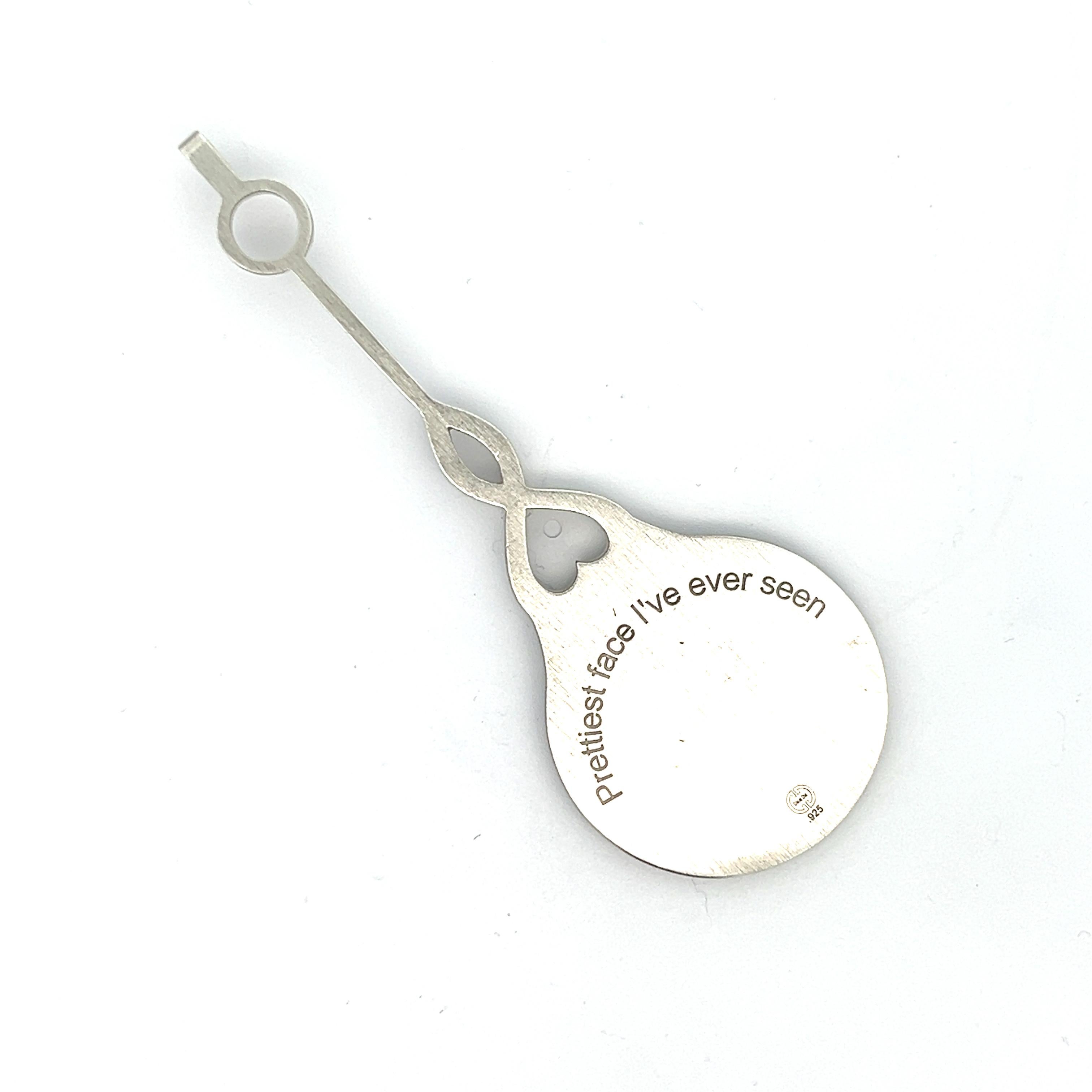 Questo incantevole ciondolo a specchio in argento Sterling è un pezzo unico e accattivante che unisce l'eleganza a un tocco di bizzarria. Il ciondolo presenta uno specchio splendidamente lavorato con un manico lungo e sottile, ornato da diamanti