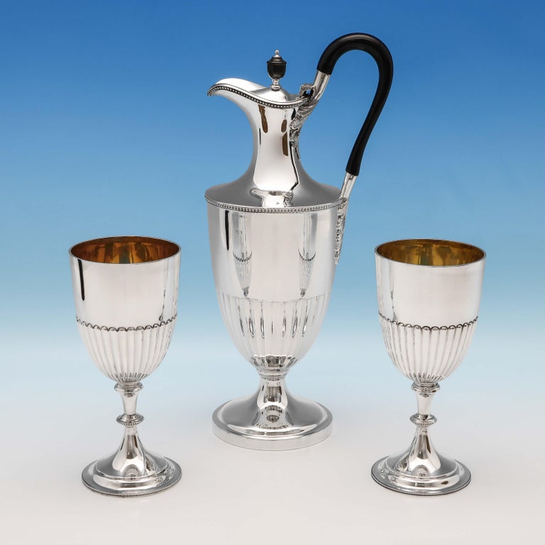 Hallmarked in London in 1895 by William Hutton & Sons, this attractive, Victorian, antique sterling silver Wine Ewer and pair of goblets, feature fluted decoration and bead borders, with gilt interiors to the goblets. Each goblet measures 6.5