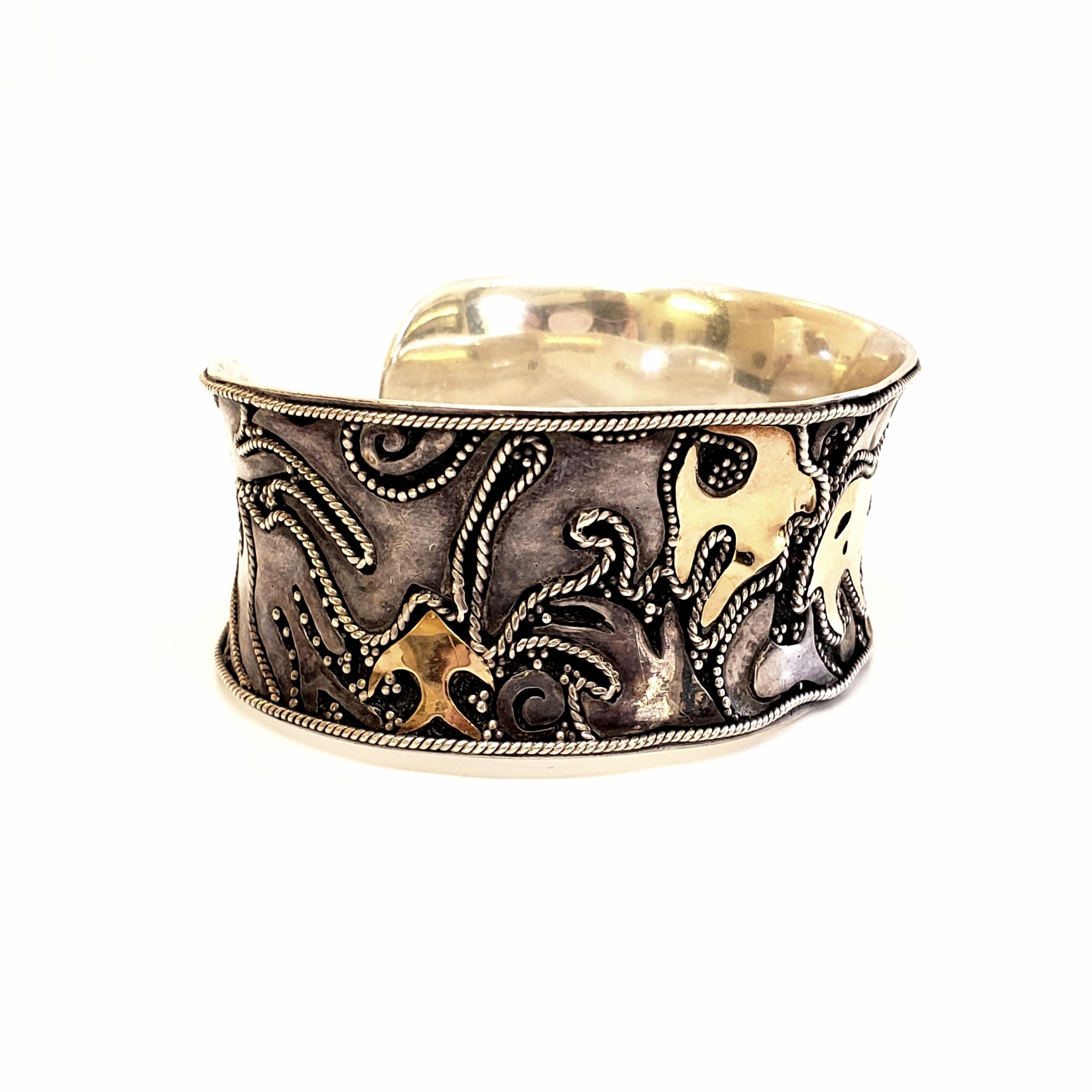 Sterling silver with gold accents cuff bracelet.

Interesting abstract design featuring what looks like and ocean motif of fish, rays, coral, waves and birds. Beautiful and high quality craftsmanship is evident.

Measures approx 6 1/4