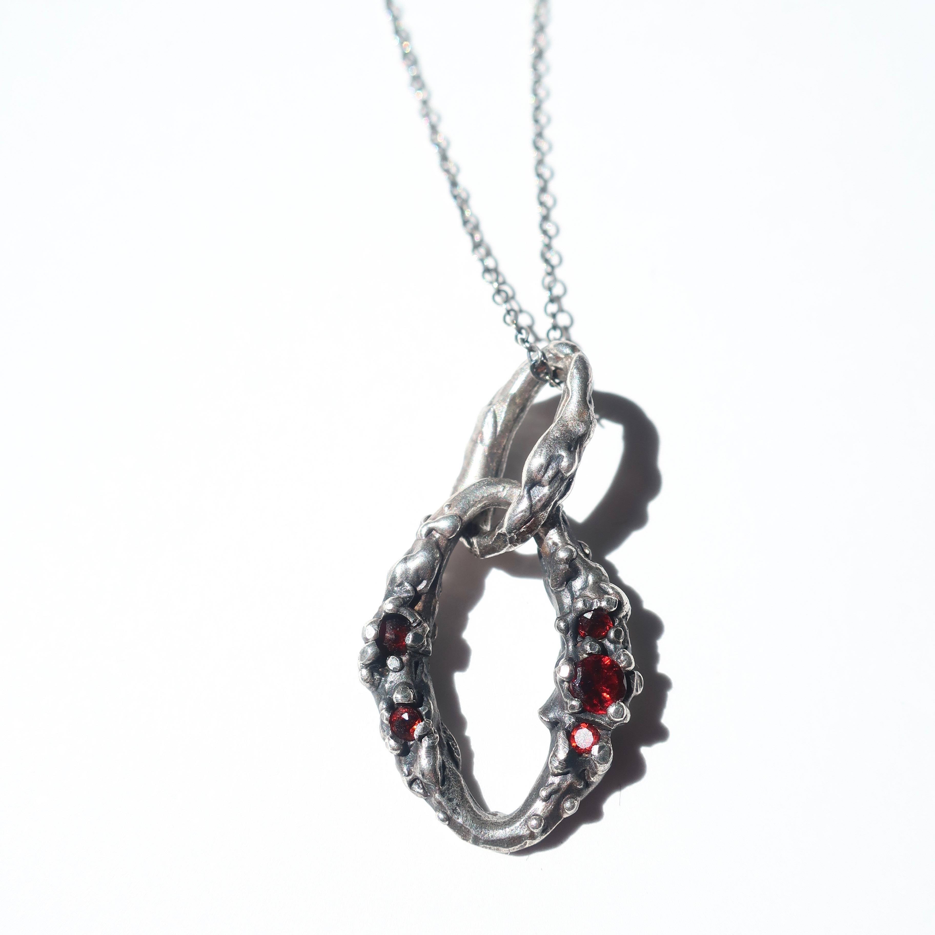 Hand crafted sterling silver pendant with a range of 3-2mm garnets on a 20 inch sterling silver chain. Pendant measures 2 inches in length. 