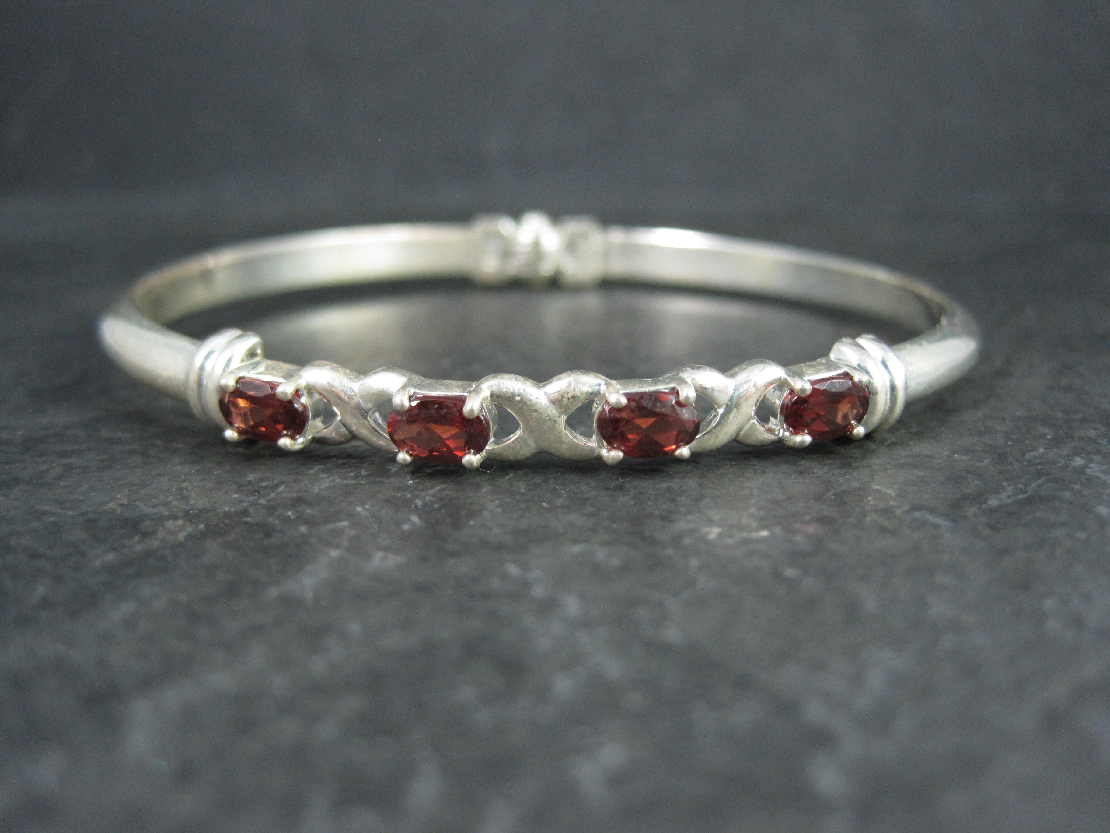 This beautiful estate bangle bracelet is sterling silver with 4 oval cut 4x6mm garnets set in an XO pattern.

The face of this bracelet measures 1/4 of an inch wide.
It has an inner circumference of 7 1/2 inches and an inner diameter of 2 3/8
