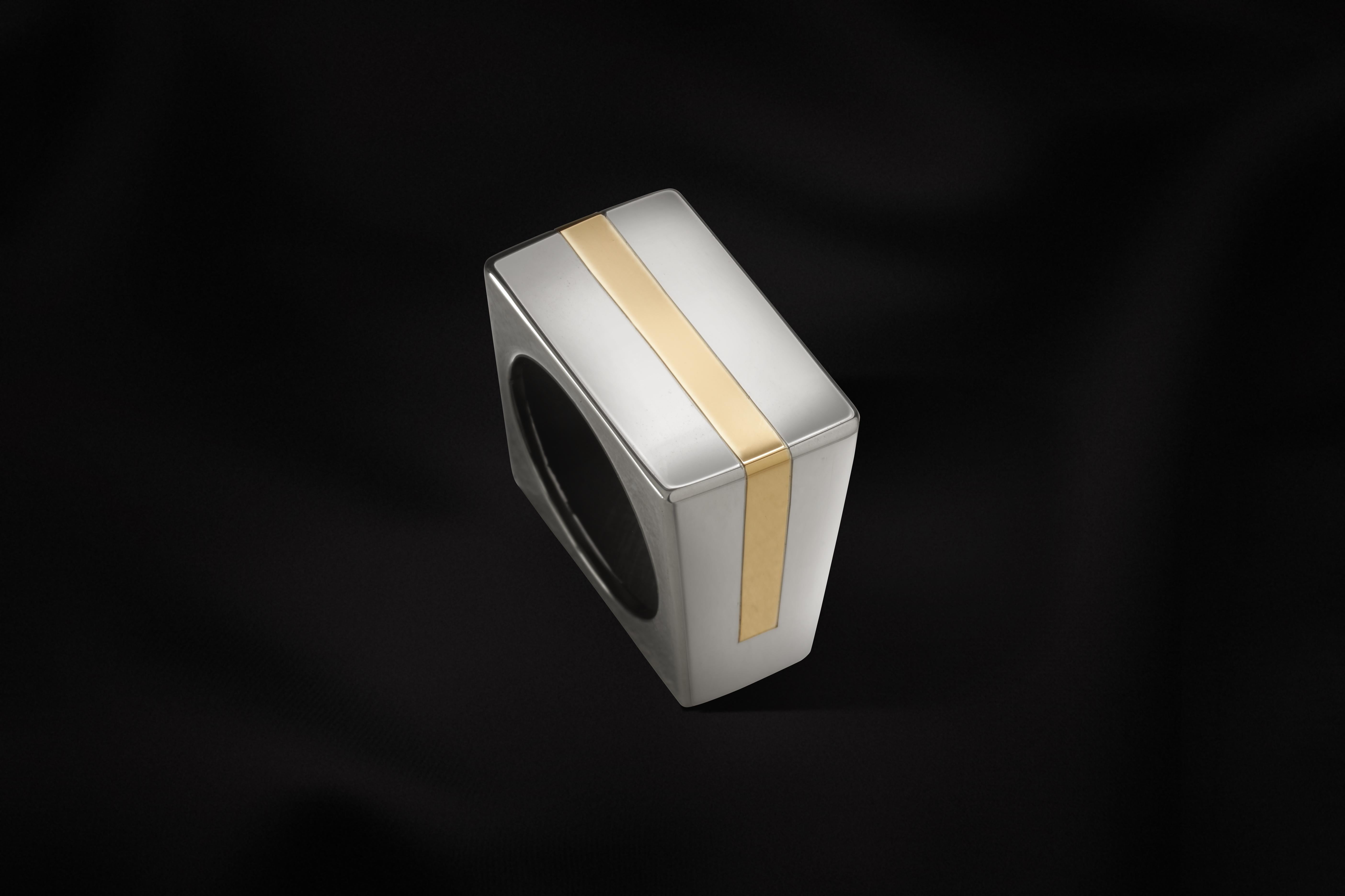 This sculptural, architechtural style ring is handmade in sterling silver and 18k yellow gold.
The base and main material of this square-shaped ring is sterling silver, and the yellow gold line makes the colour contrast.
It has been designed and