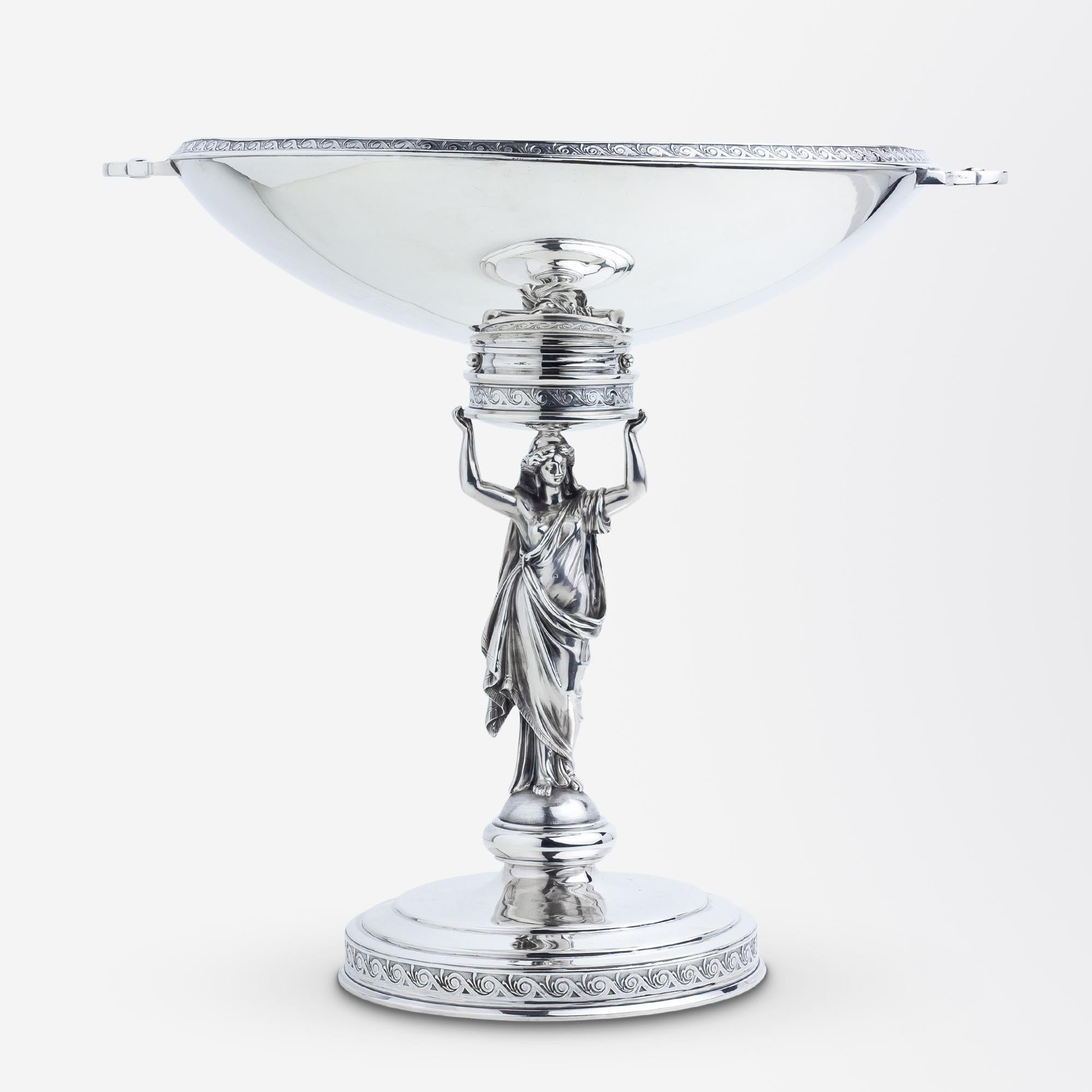 This rather glorious sterling silver tazza or footed comport was likely made by John R. Wendt in the 1870s. The figural piece features a stepped circular base which is topped by a classical figure of a woman in a robe which is holding atop of her