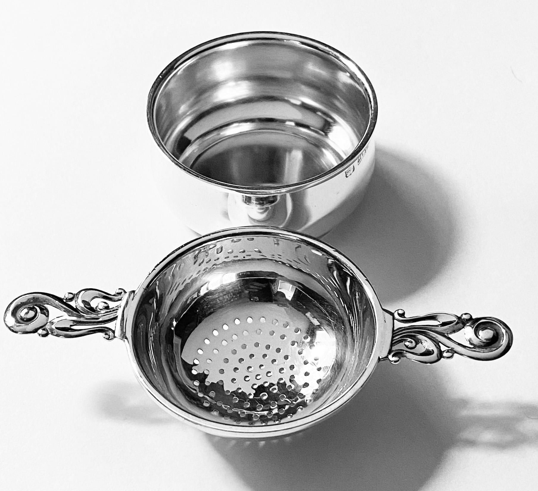 Sterling silver tea strainer with stand, Mappin and Webb Birmingham 1961. Perfect condition, simple design, strainer with nice pierced bowl and elongated scroll foliate handles. Fully hallmarked on both pieces and also stamped under base Mappin &