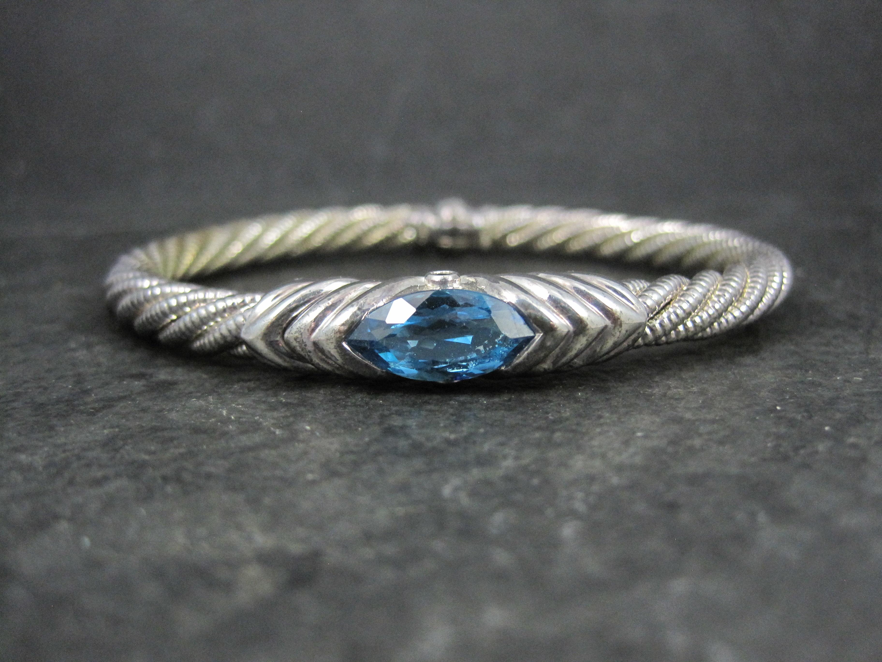 This gorgeous estate bangle bracelet is sterling silver.
It features a 7x14mm marquise cut blue topaz and 2 round 2mm sapphires.

Measurements: 3/8 of an inch at its widest point, Inner circumference of 6 3/4 inches, Inner diameter of 2 by 2 1/2