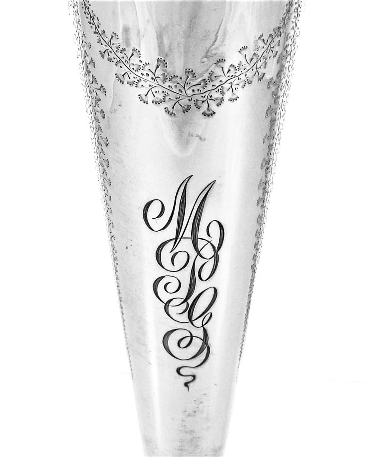 Schleifen, Kränze und Blumen verleihen dieser Vase aus Sterlingsilber eine zarte, feminine Note. Sie ist oben breiter und verjüngt sich nach unten hin, so dass sich die Blüten schön ausfüllen können. Um den Sockel herum sind ähnliche Ätzungen wie