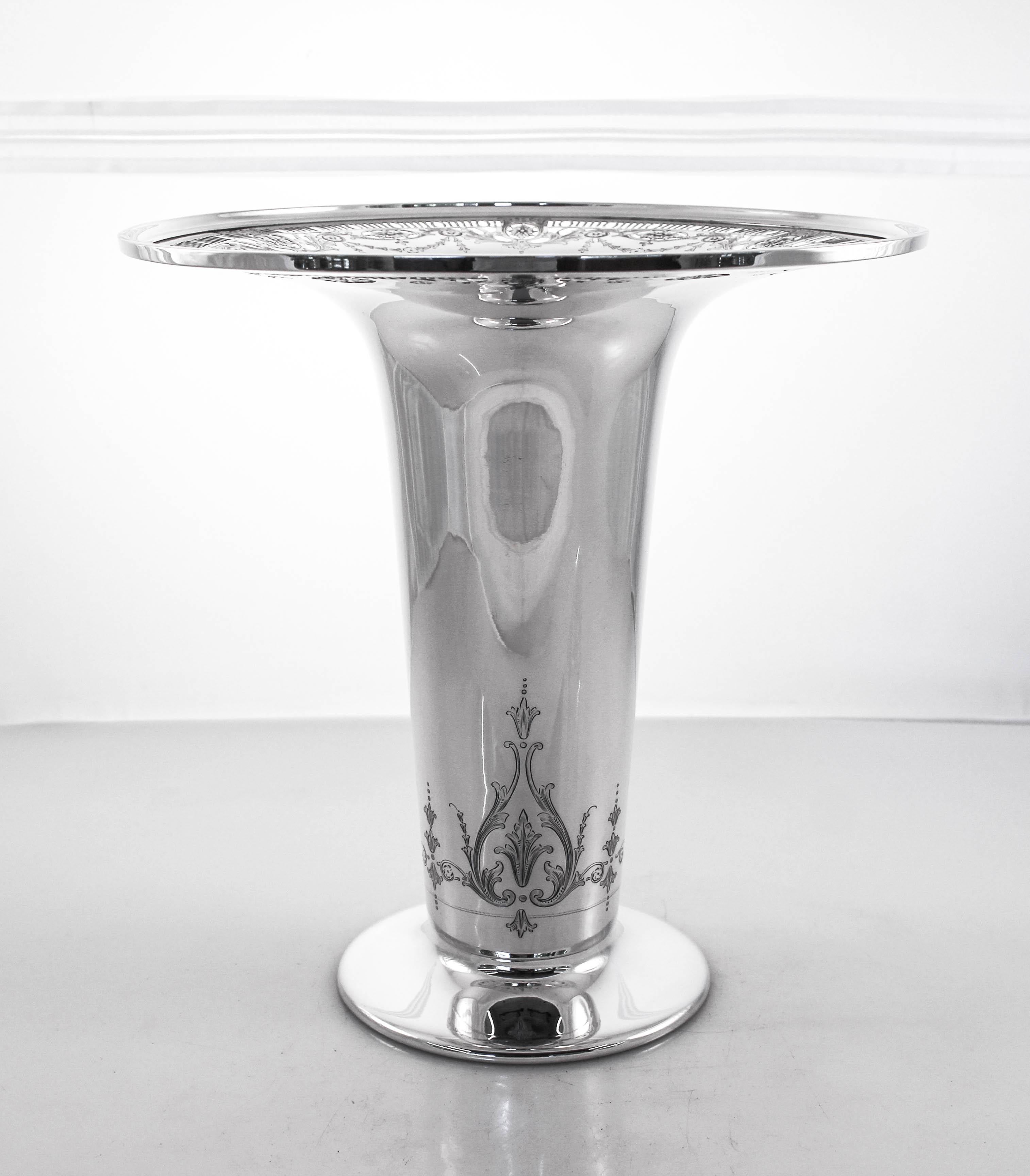 We proudly offer this sterling silver whiting vase from 1916. It has a large rim with a beautiful reticulated design and etched wreaths and bows interspersed. Along the bottom, just above the base, which is not weighted, there is a pristine etched