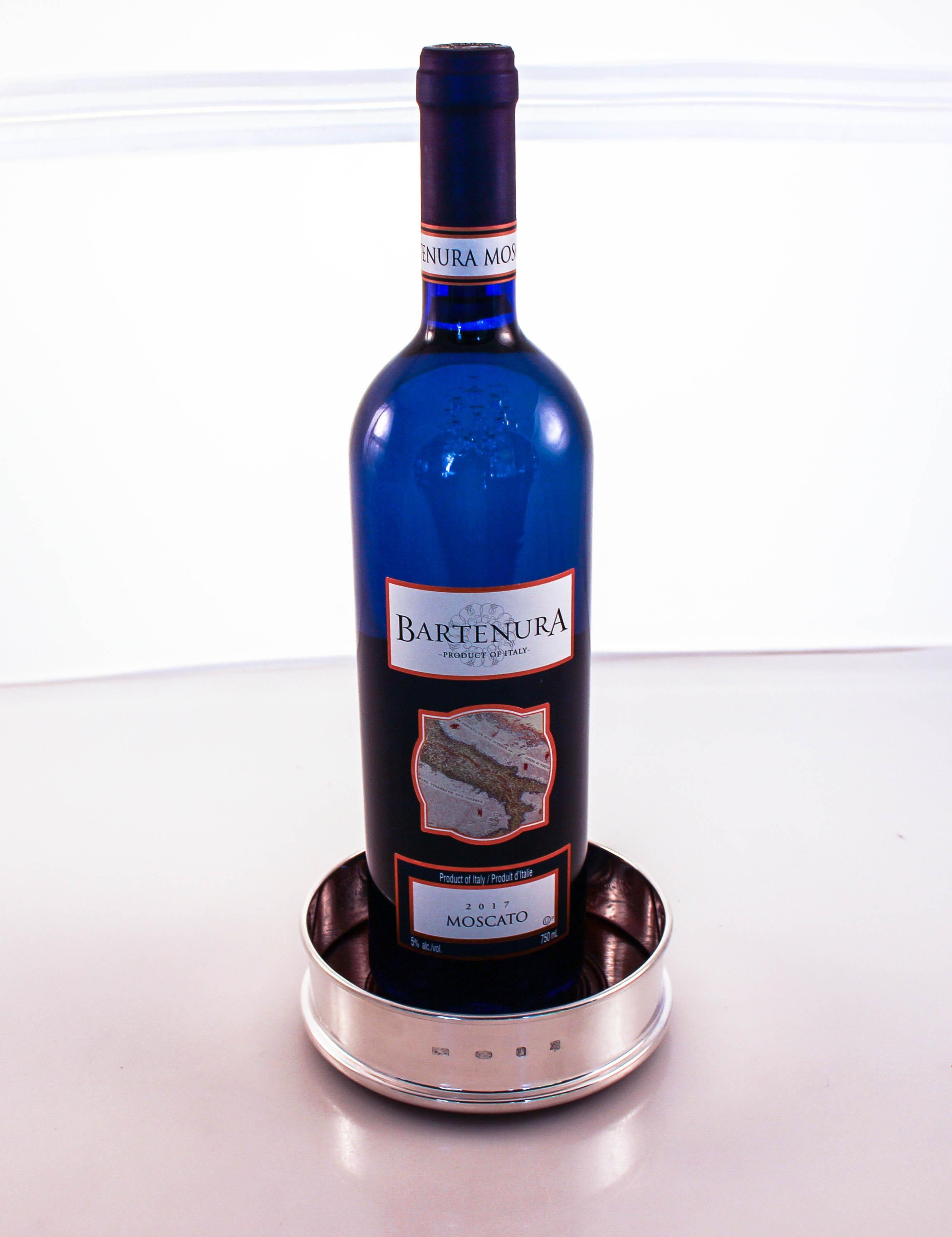 We are delighted to offer this sterling silver wine coaster. It is new and made in England. It has a tall rim that envelopes the bottle with a wood bottom and again sterling in the center. Go ahead and dress up your dining room table with this