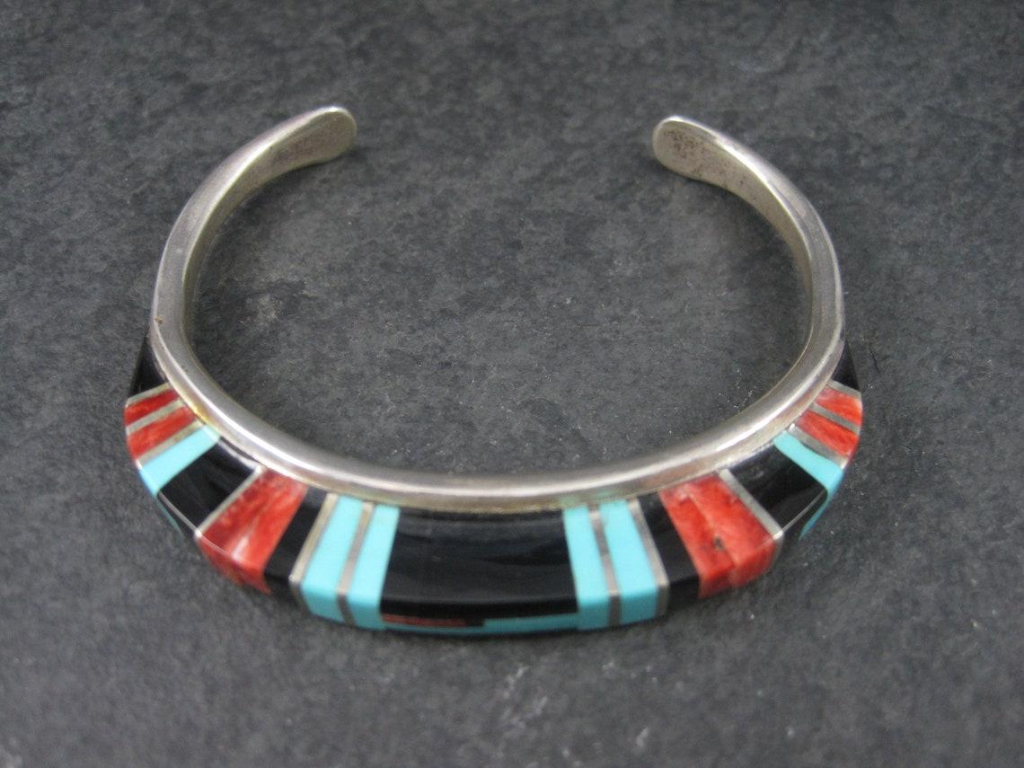 This gorgeous bracelet is the creation of the famed Zuni silversmith couple Bryce and Erma Eustace.

Though the raised inlay has always been Erma's signature design, this bracelet is not typical of her pieces. This bracelet is more narrow and the