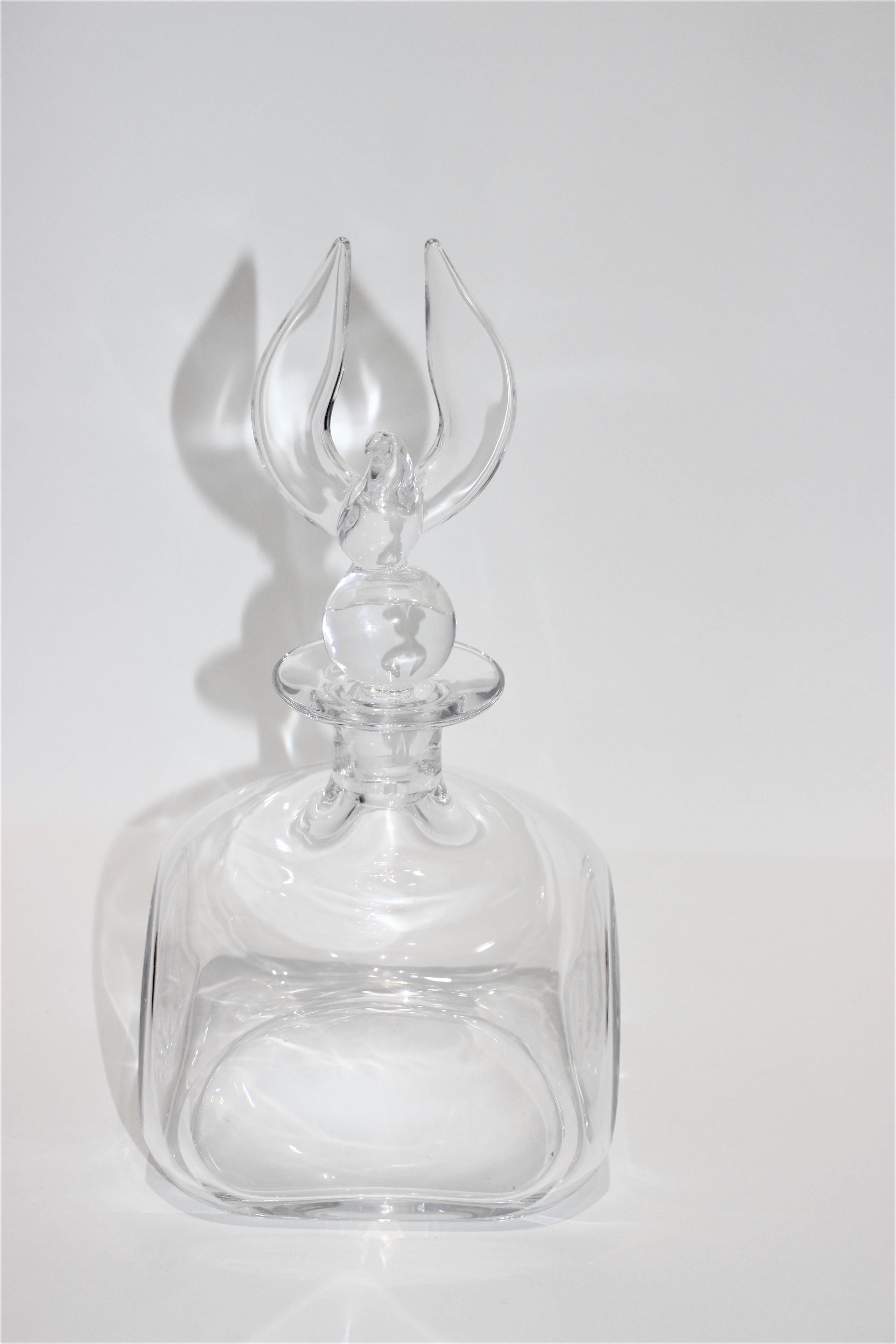 Carafe en cristal de Steuben avec bouchon à aigle américain sur une boule, un globe stylisé du monde, conçu par Lloyds Atkins, elle a été introduite pour la première fois en 1973 et n'est plus en production.

Signé au verso - voir dernière