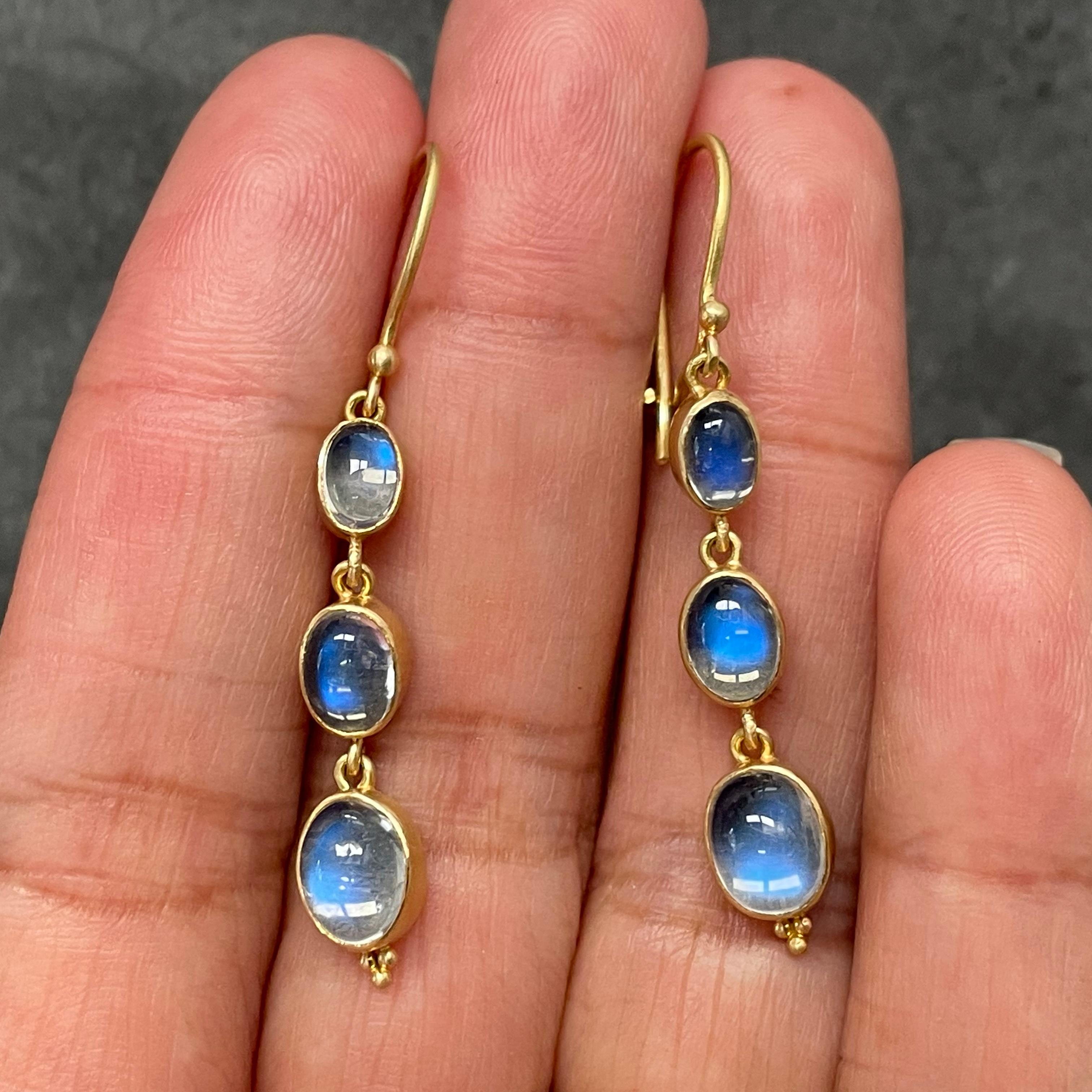 Three oval cabochons of graduated sized rainbow moonstone ( 4x6, 5x7, and 6x8 mm ) set in simple matte-finish 18K gold bezels dangle below safety clasp wires in this simple yet elegant design.  You can't go wrong with the beautiful shimmering blues