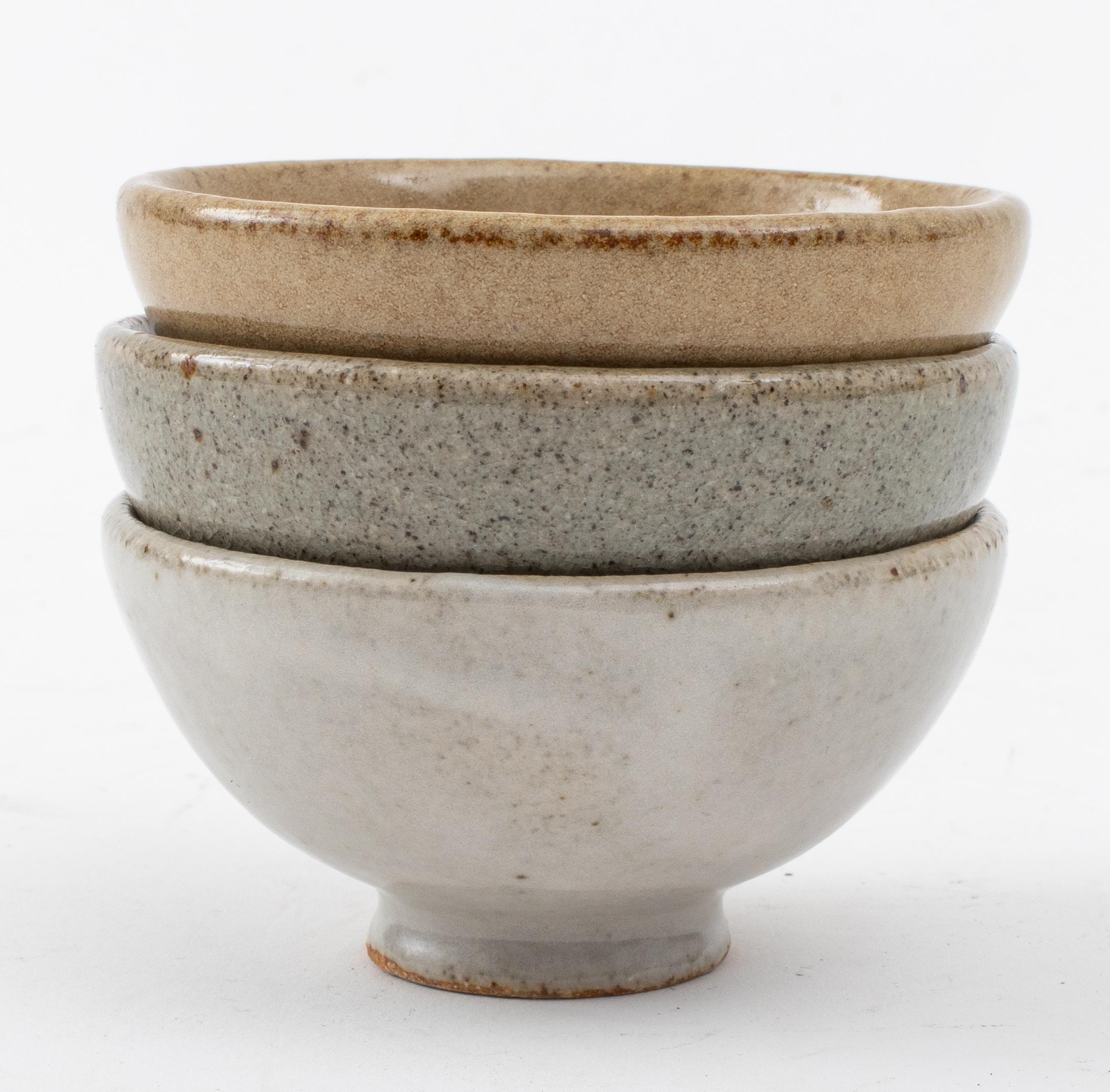 Steve Friedlander (attr., American, active 1964 - 1985) Glazed ceramic footed sake cups, (three) with grey, taupe, and blue stoneware glazed, the under side of each cup marked SF in square. 
Measures: 1.5