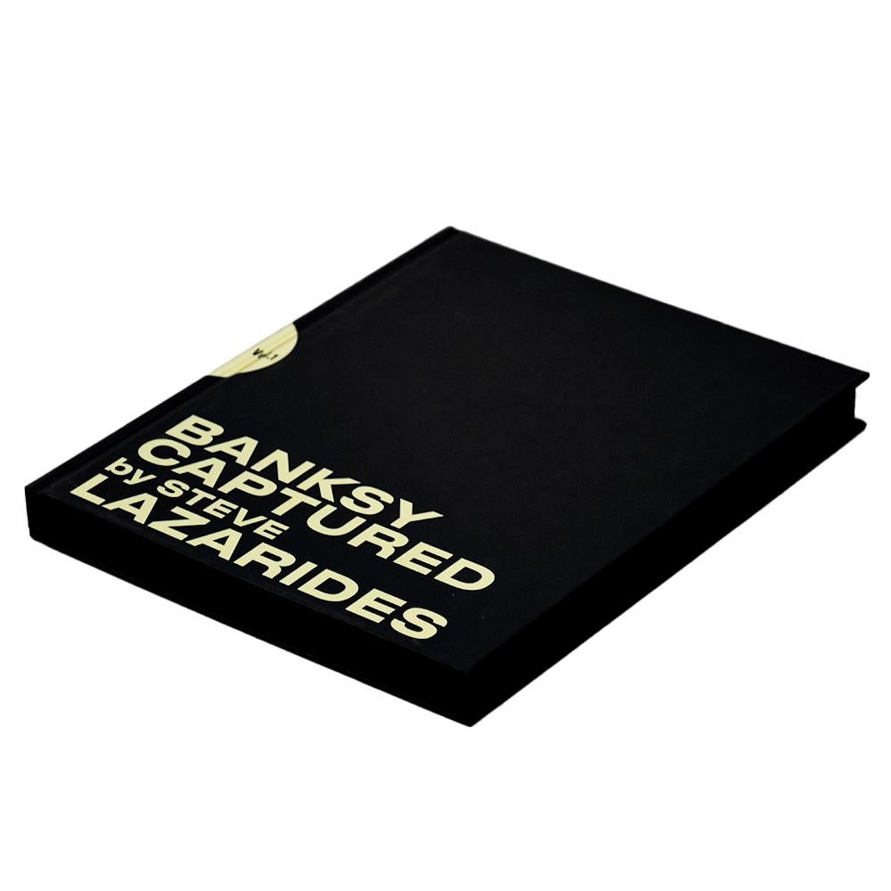 Collectional de photos d'art de Banksy. Volume 1 Hardcover par l'ex-manager de Banksy, Steve Lazarides.
Édition limitée à 1000 exemplaires. Numéroté à l'intérieur du livre.
Comporte de nombreuses images inédites de Banksy (visage couvert) et des