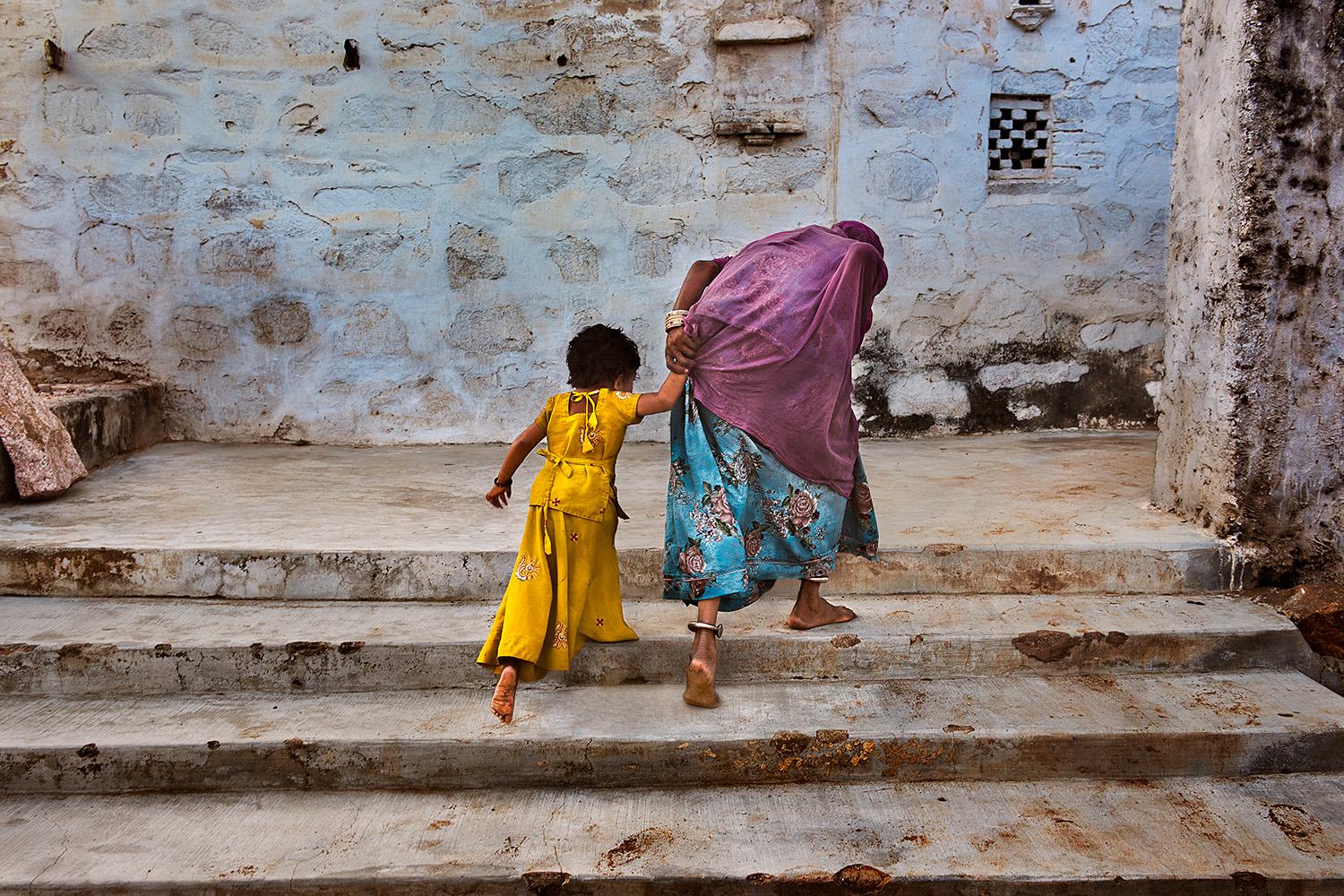 Steve McCurry Color Photograph – Eine Großmutter nimmt ihre Enkelin mit nach Hause