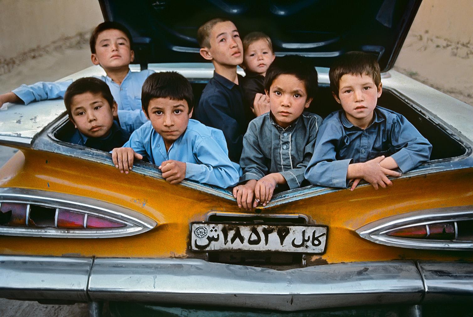 Steve McCurry Figurative Photograph – Jungs im Kofferraum eines Taxis