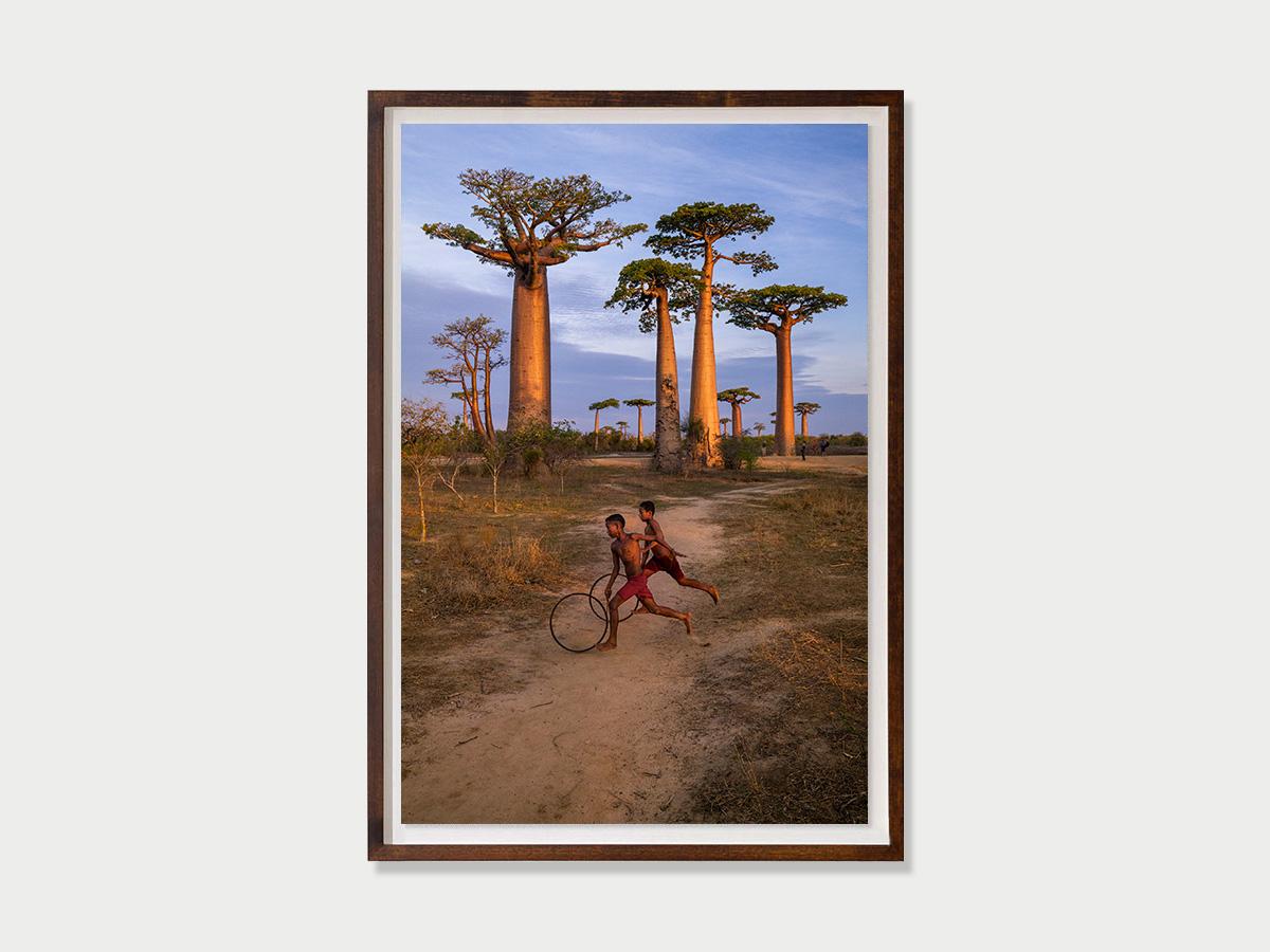 Les garçons qui courent avec des créoles, Baobab Avenue, Marondava, Madagascar, 2019 - Marron Color Photograph par Steve McCurry