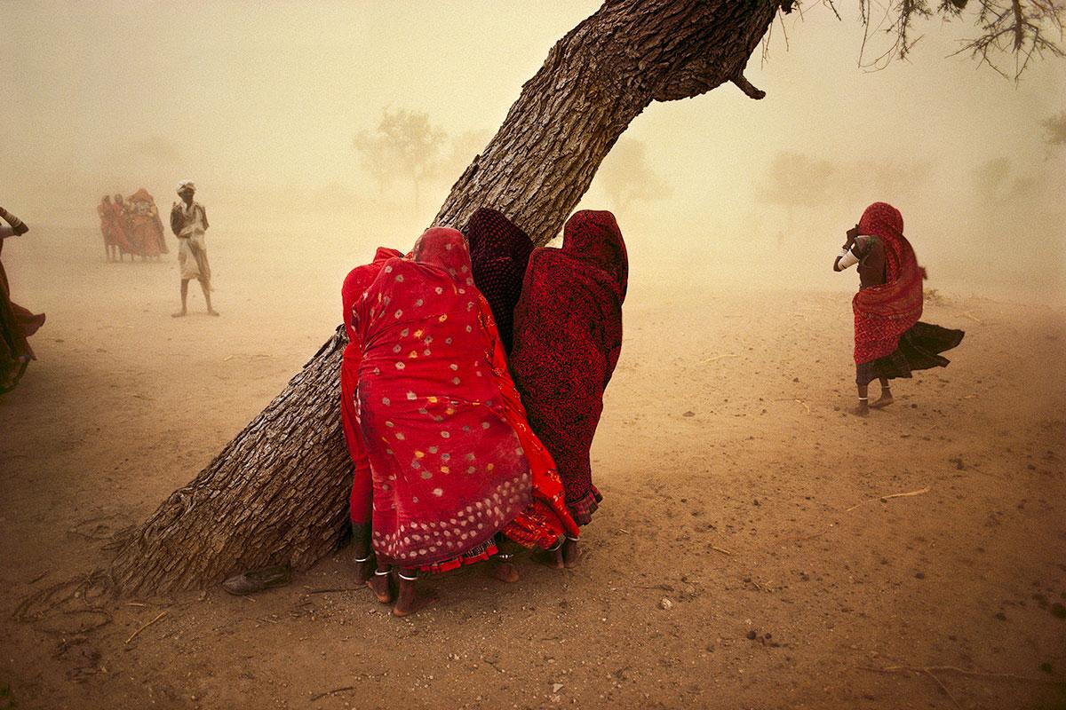 Steve McCurry Landscape Photograph - Women seek shelter from the dust storm, Rajasthan, India