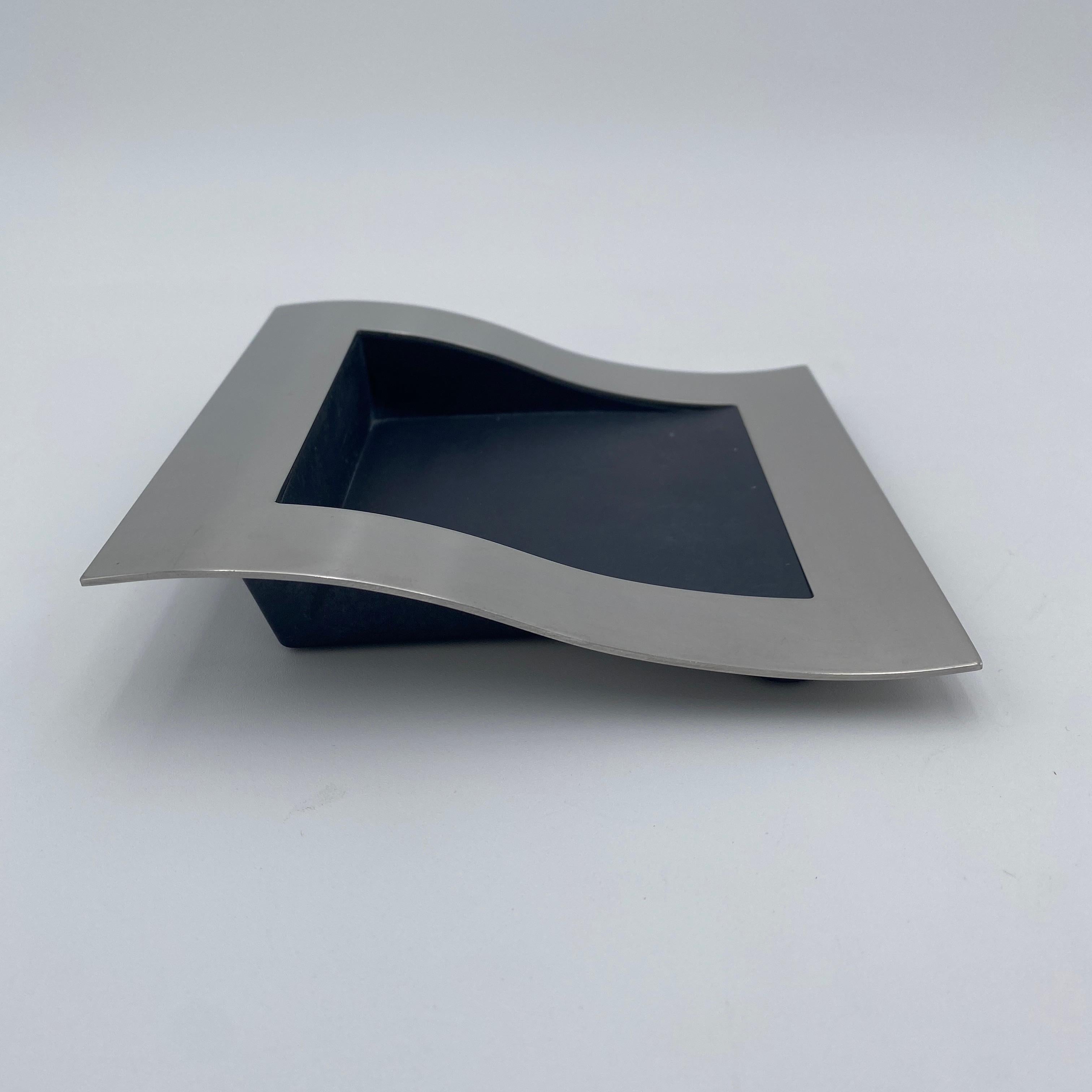 Questo portacarte della serie Wave di Royal Copenhagen, creato da Steve McGugan nel 1992, è una bellissima aggiunta a qualsiasi collezione. Realizzato in acciaio inossidabile di alta qualità e prodotto in Danimarca, è una vera e propria opera