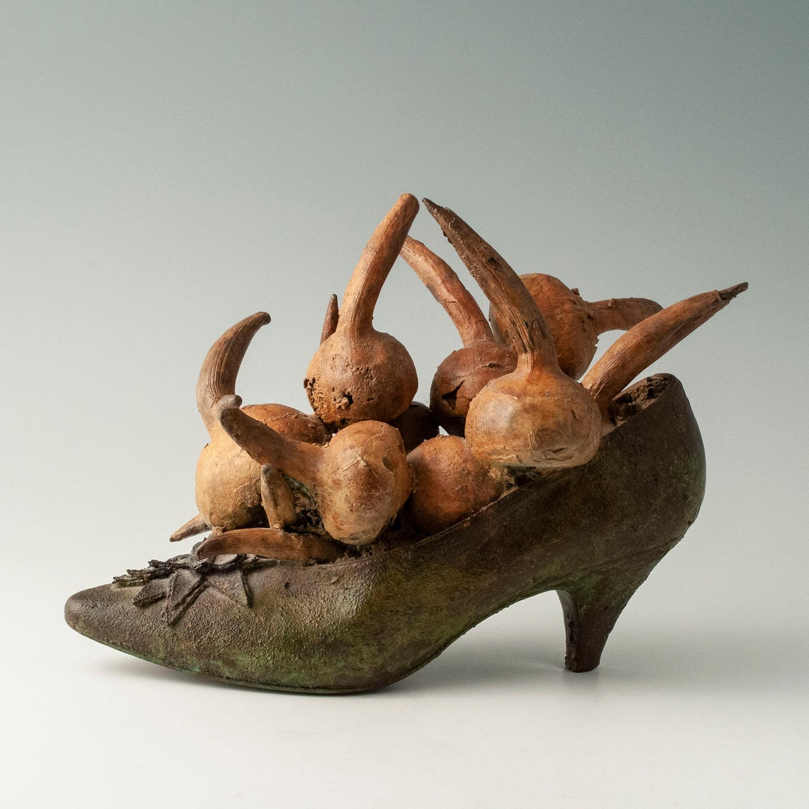 Steve Tobin (geb. 1957) ist ein amerikanischer Bildhauer, der hauptsächlich in Bronze, Stahl, Ton und Glas arbeitet. Dieser skurrile Bronzegussschuh mit Zwiebeln gehört zu einer Serie von 100 Exemplaren, die er mit verschiedenen Gemüsesorten, Obst