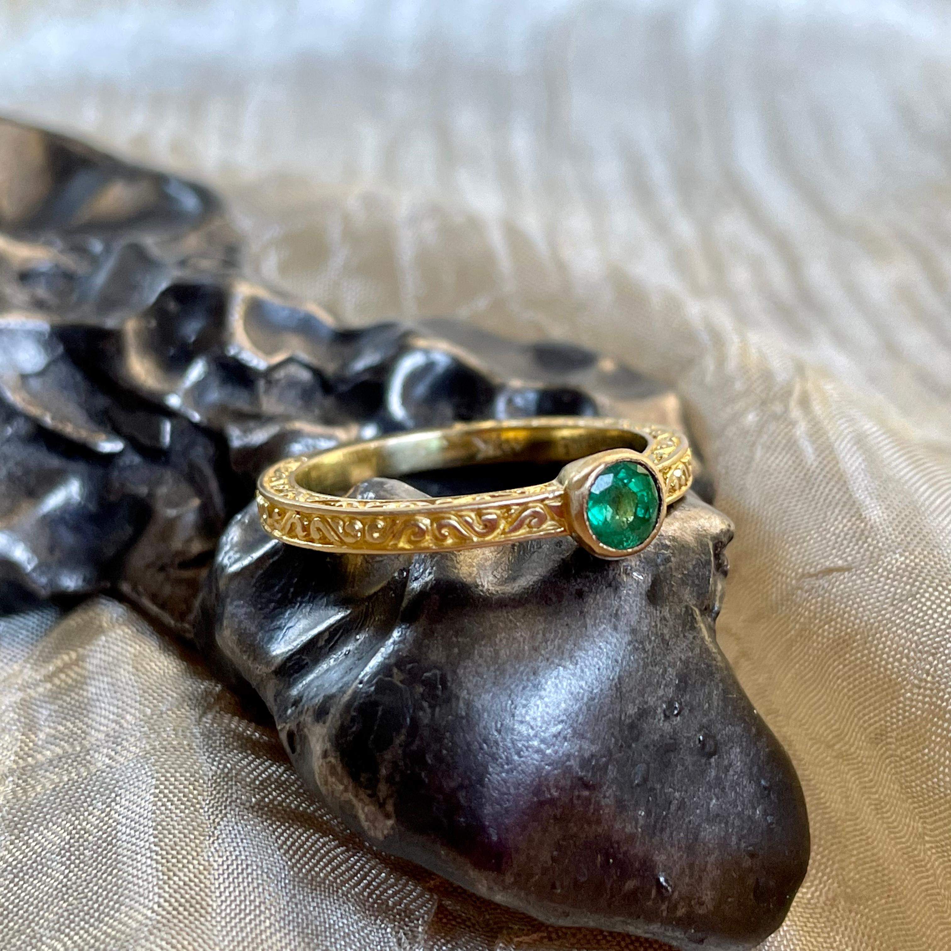 A lively, translucent, 4 mm Zambian emerald faceted held in a signature design Steven Battelle ancient-inspired ring design in 18K matte-finish gold.  This beautiful ring is currently sized 6.5.  It is resizable.