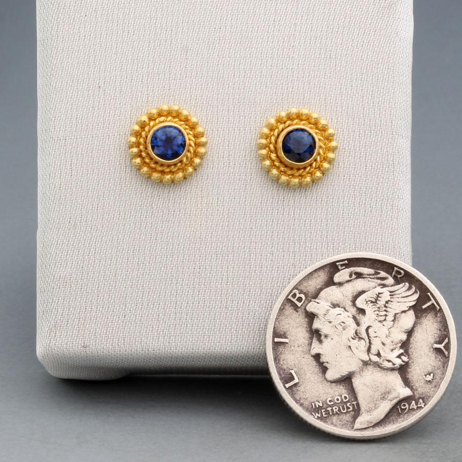 Deux saphirs bleus ronds à facettes de 3 mm de diamètre sont entourés d'un chaton en 
