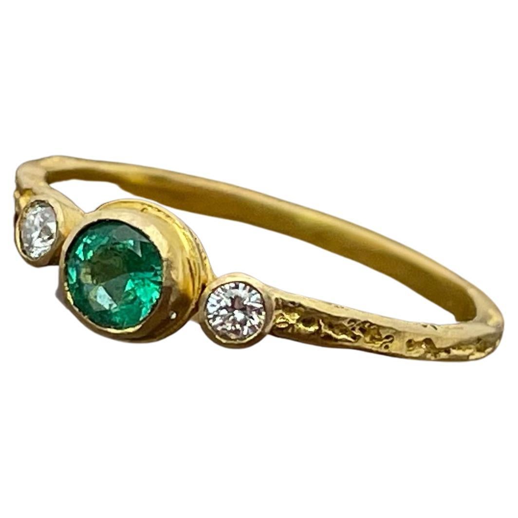 A bright 4mm round faceted Emerald is set in an organic textured squarish shank surrounded by two 2mm VS1 diamonds.  The gold is matte-finish. This ring is currently sized 6.5, but is resizable.  Just a really subtle and sweet ring !                