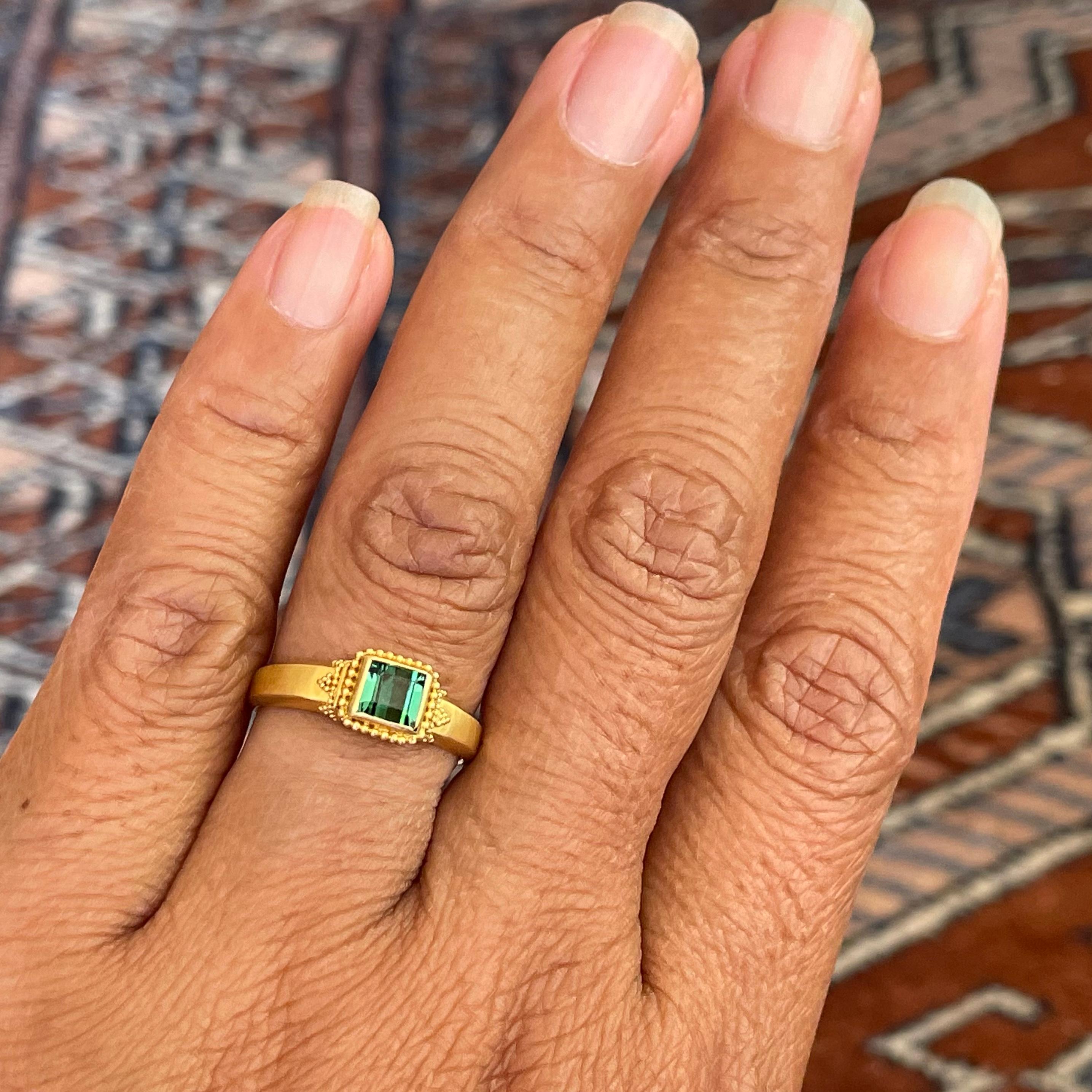 A crystalline 5 mm square cut green tourmaline is the centerpiece for this masterful handmade high karat geometrically granulated ring. The tapered and beveled matte-finish shank is sized 6 1/4.   This ring is resizable. Elegant!