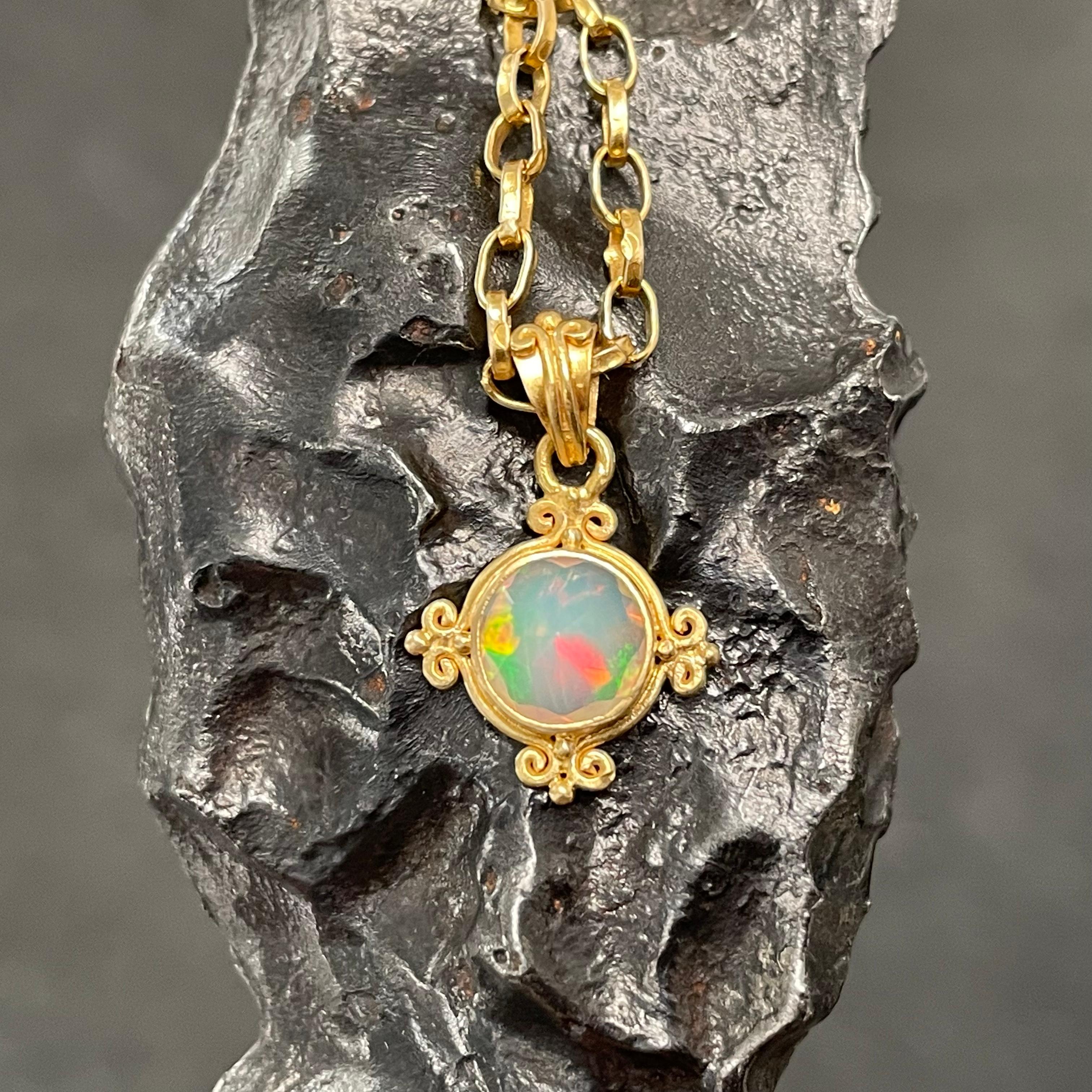 Une ardente opale ronde de 7 mm à facettes de la mine de Welo, en Éthiopie, est sertie dans une délicate étreinte en or 18K à quatre côtés, faite à la main, en forme de 