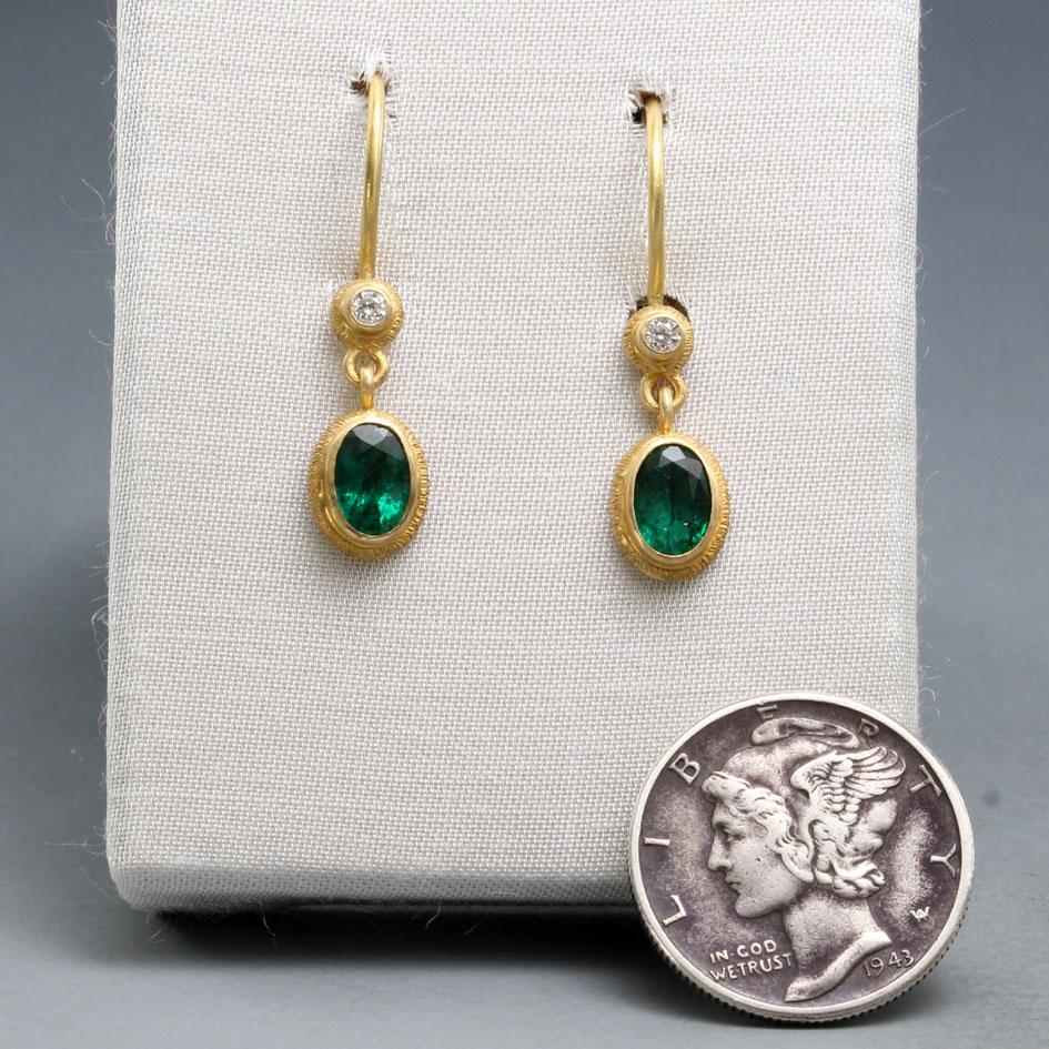 Two deep green 4 x 6 mm oval faceted Zambian emeralds dangle below sparkling 1.8 mm VS1 diamonds, both surrounded by rich line textured wide 18K bezels in these handmade beauties.  All done in matte-finish on sturdy safety-clasp wires.  Simple,