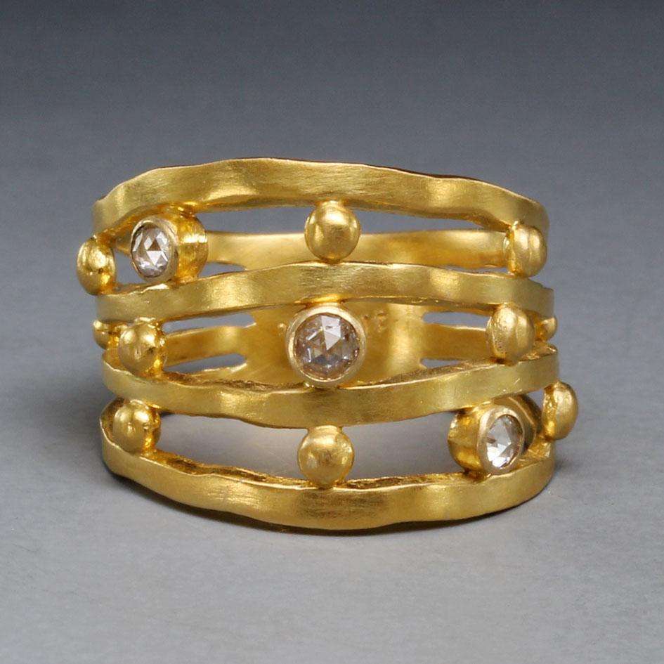 Four slightly wavy squarish 18K gold bands are interspersed with various sized handset 