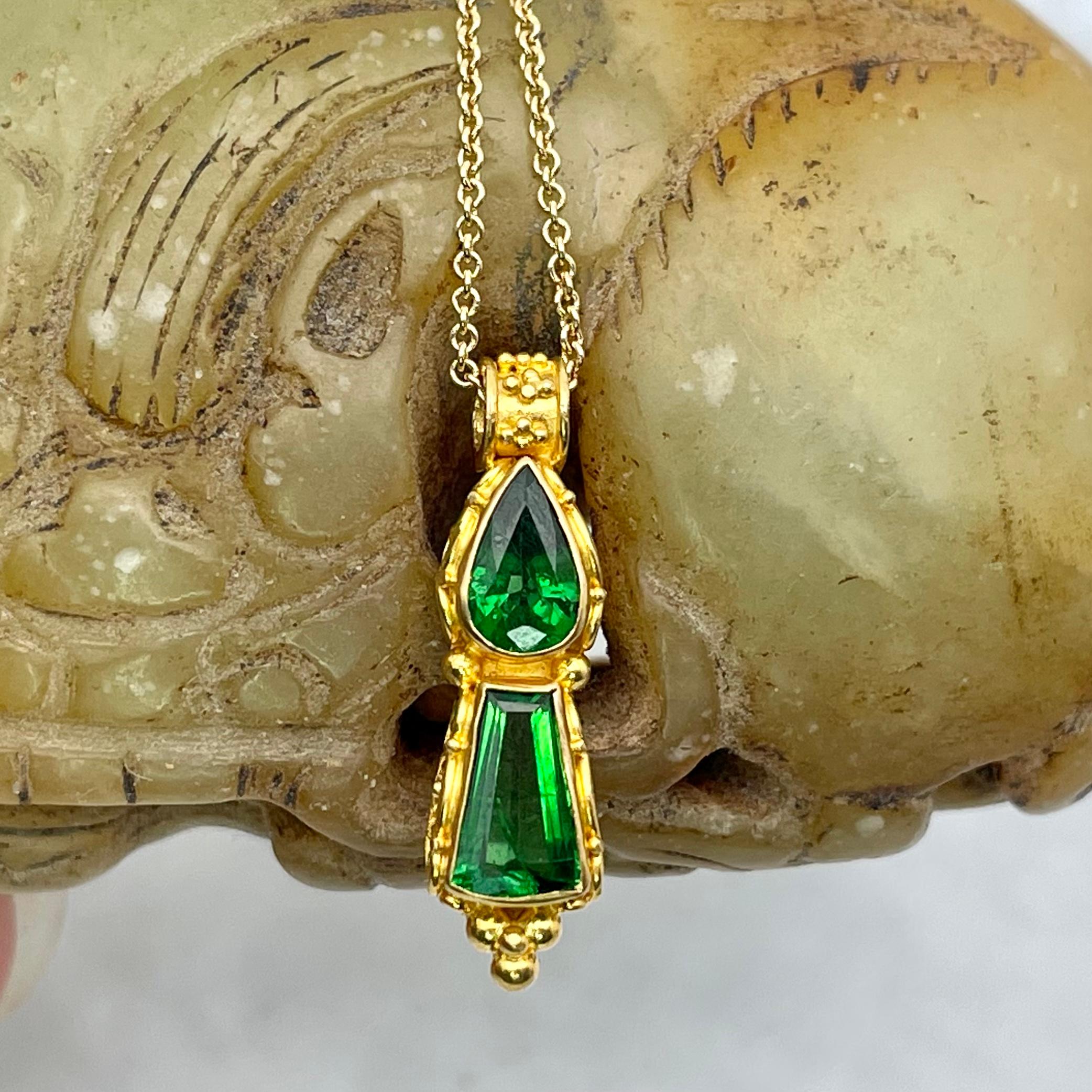 Brilliant green 4 x 6 mm pear shaped and 5 x 7 mm trapezoidal faceted tsavorite garnets are surrounded with intricate 22K wire and scrollwork accents in this example of classic handmade artisanship. Note that the bail size is fairly narrow, about 3