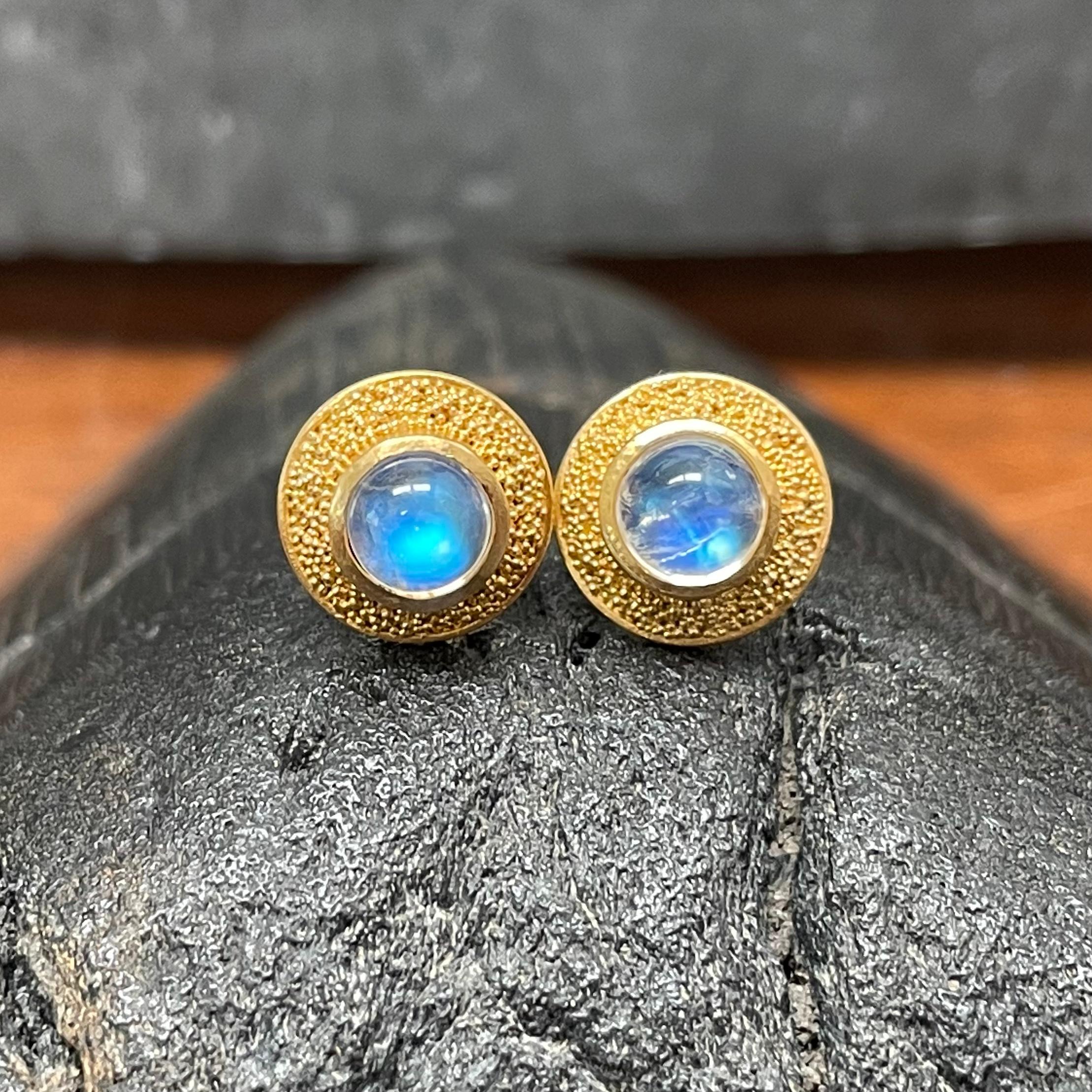Two lively blue shimmering 5 mm rainbow moonstone cabochons  are surround by complementary fine 