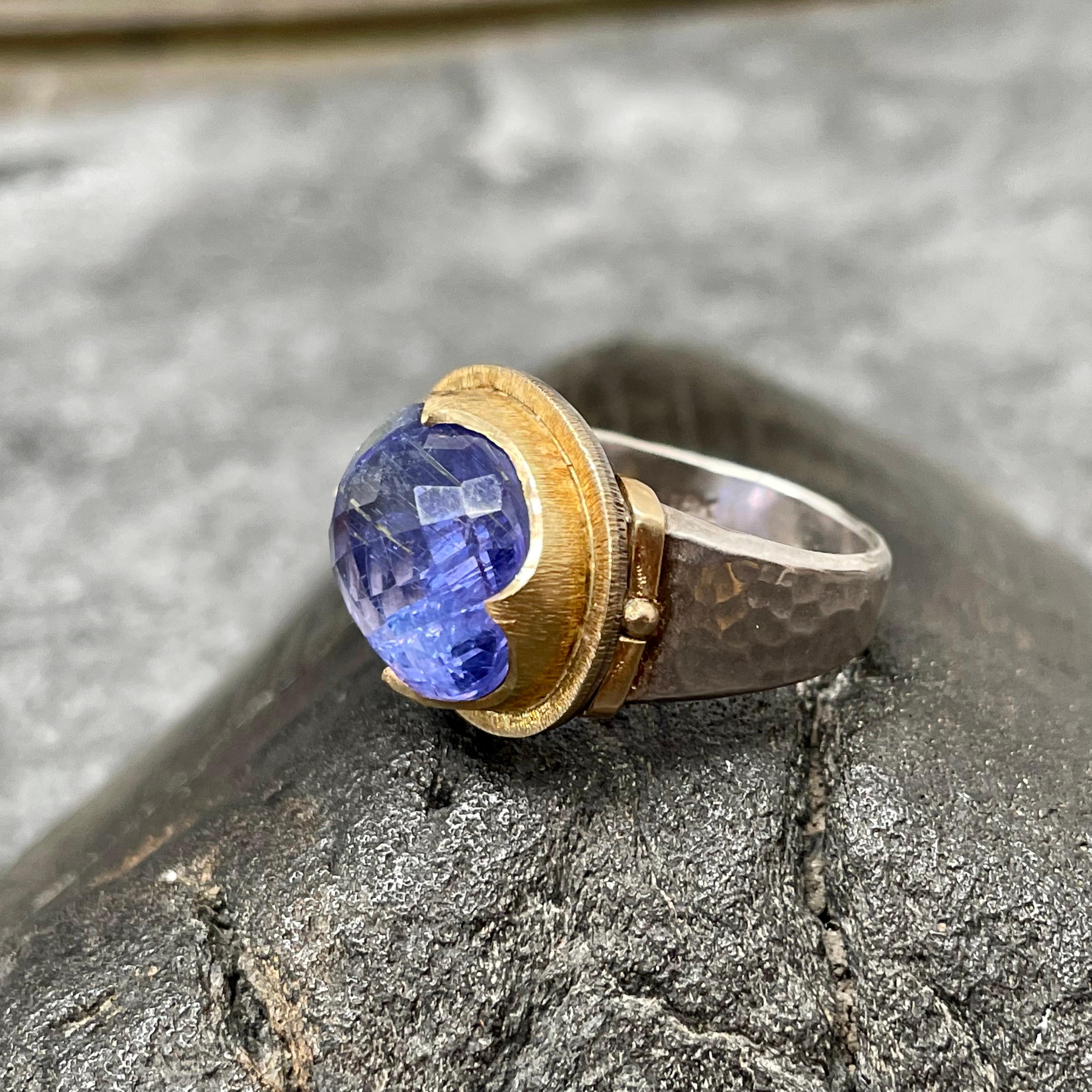 Una tanzanite ovale con sfaccettatura rosa di 12 x 15 mm è racchiusa in un castone di ispirazione medievale con texture a 