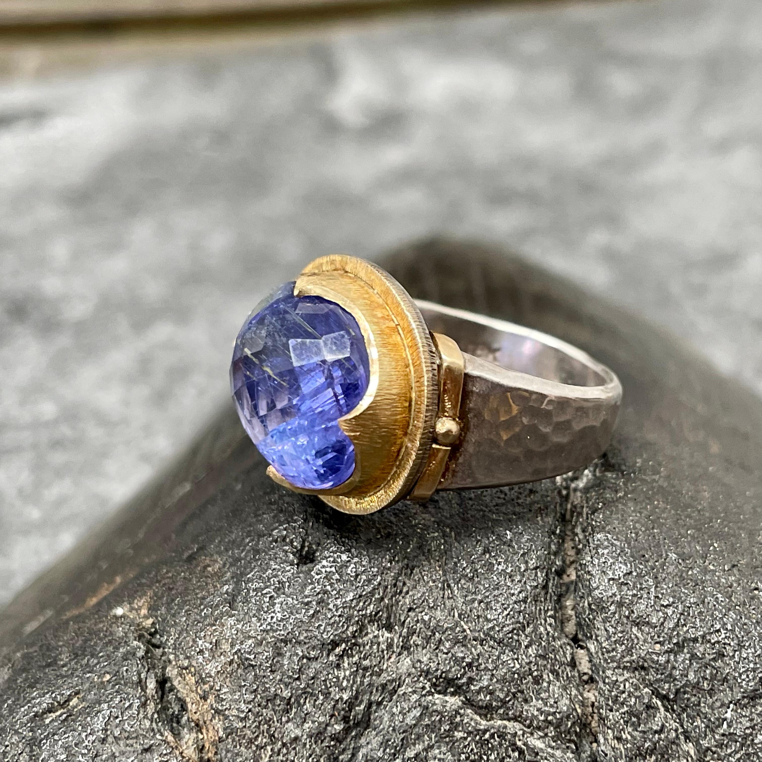 Une tanzanite ovale à facettes roses de 12 x 15 mm est maintenue dans un chaton d'inspiration médiévale à texture linéaire en 4 points, entouré d'un double chaton à texture linéaire assorti, le tout sur une large tige en argent martelé au fini gris