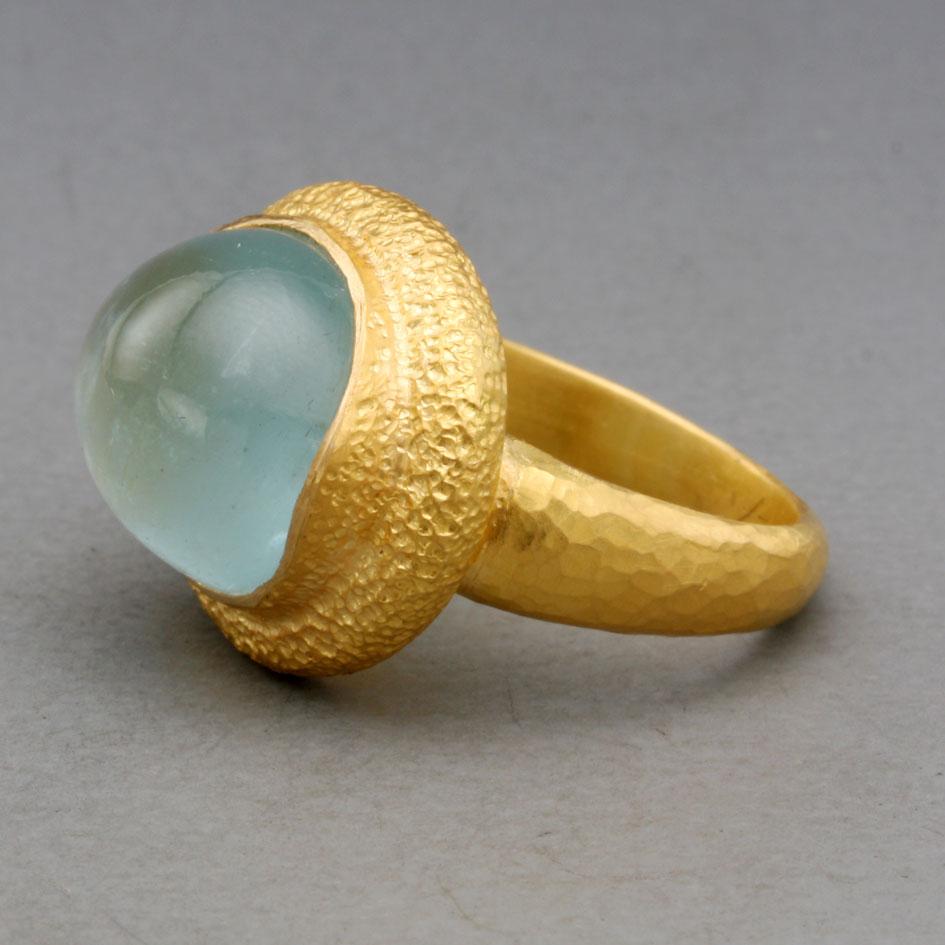Un cabochon d'aigue-marine lumineux et limpide de 11 x 14 mm repose horizontalement dans une large étreinte d'or haute qualité texturée à la main dans cette...  magnifique pièce.  De belles couleurs et formes organiques pour votre admiration.