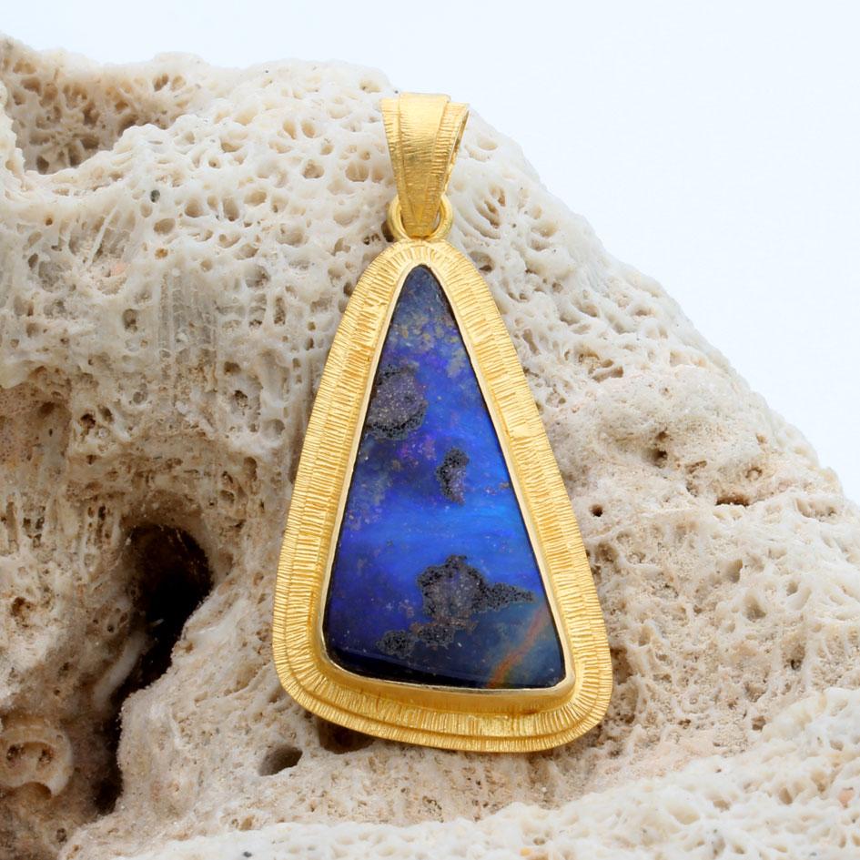 A deep blue 13 x 25  mm triangular cabochon of Australian Quilpie boulder opal is mounted in an artisan crafted 