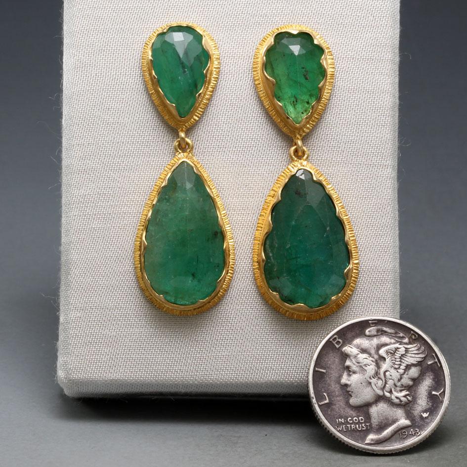 Two opposing pairs of brilliant green faceted pear shaped emeralds of approximately 7 x 10 mm and 10 x 18 mm are set in 