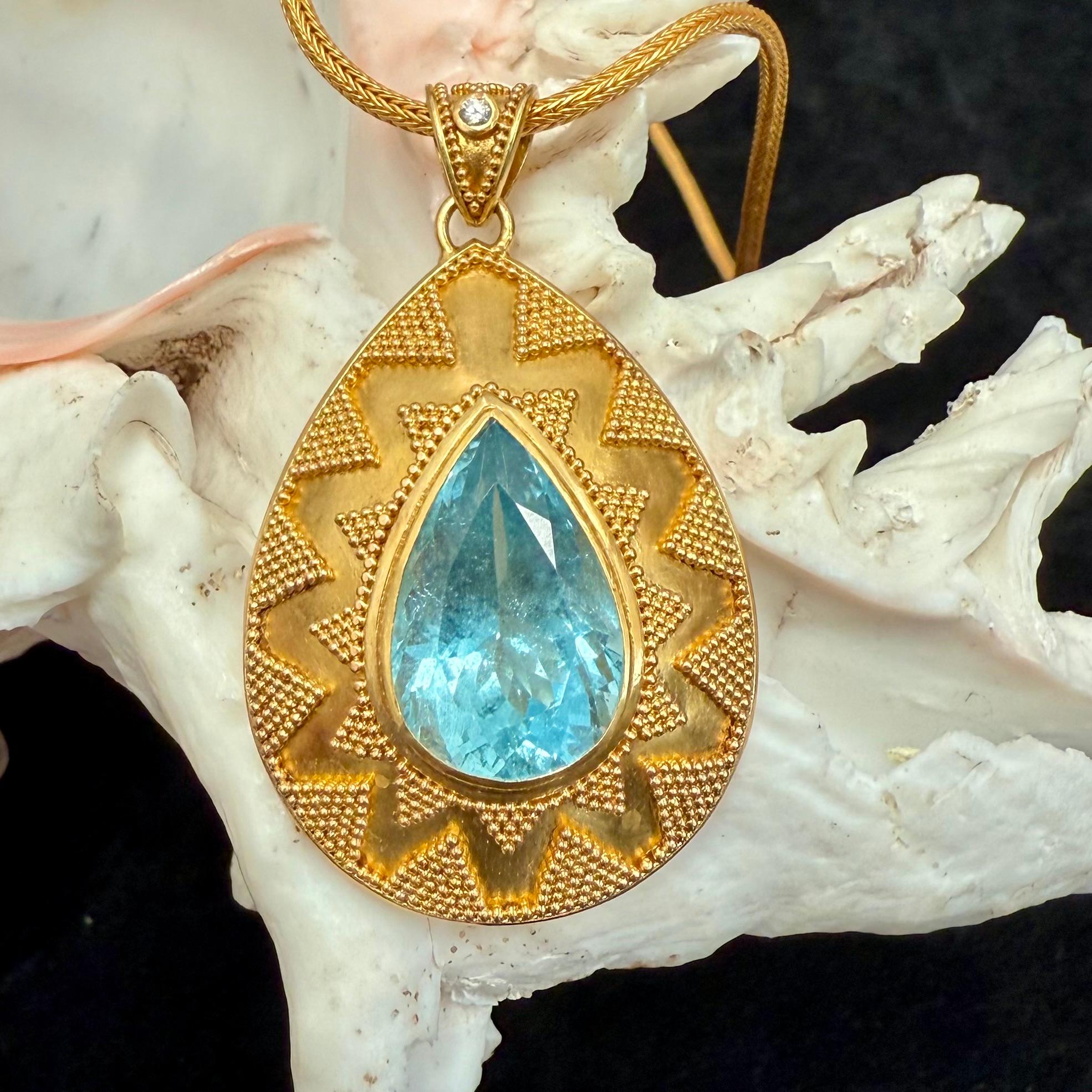 Un'acquamarina cristallina sfaccettata a pera di 13 x 20 mm di diametro è inserita in un ciondolo in granulato d'oro 22K realizzato a mano in stile etrusco, con un piccolo diamante d'accento nella cappa... L'acquamarina, la pietra natale di marzo,