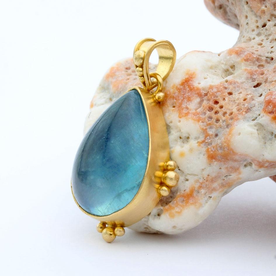 Ein saftig meerblauer, 13 x 18 mm großer, birnenförmiger Aquamarin-Cabochon wird in einer matten 18-karätigen Goldlünette mit großer/kleiner 