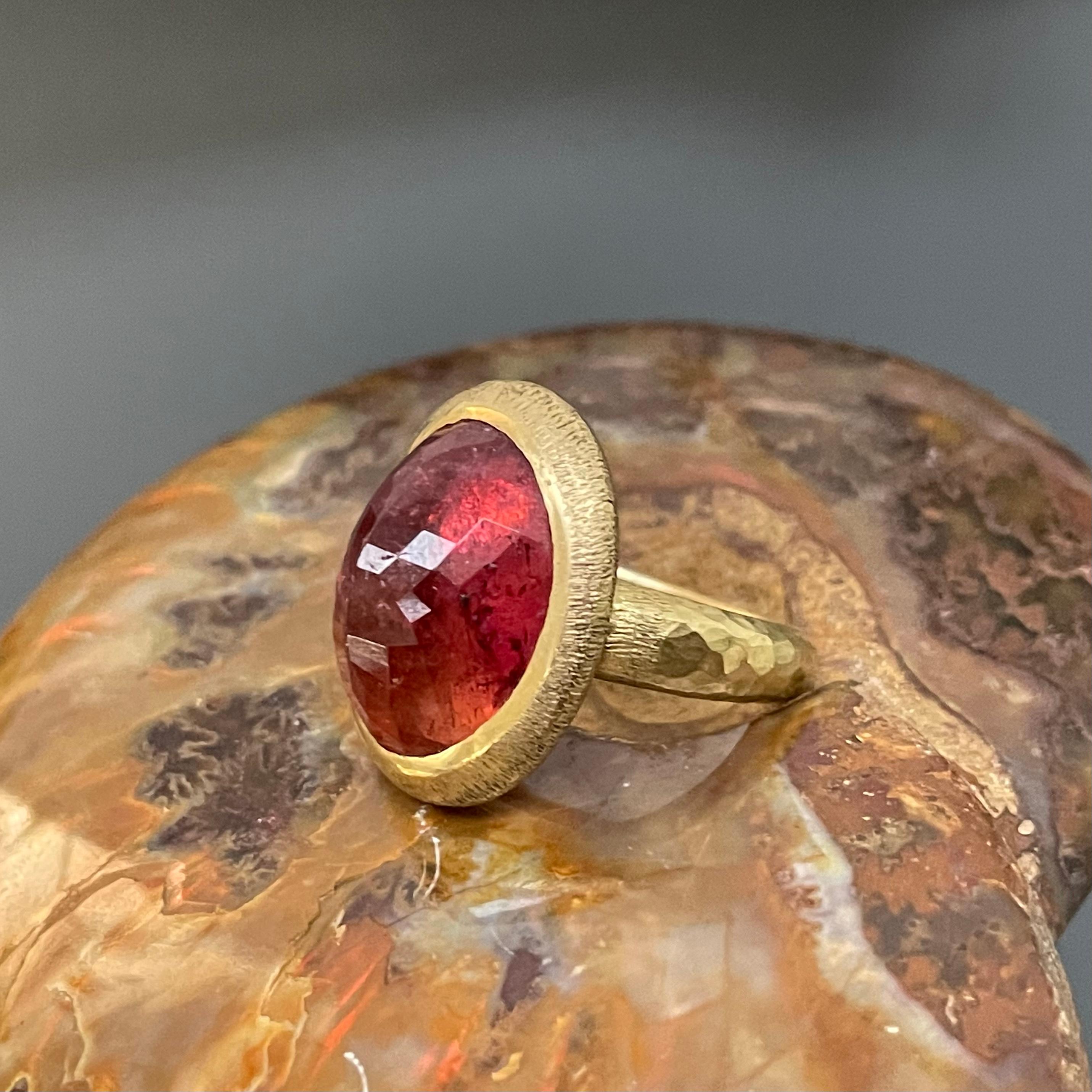 A lively, reddish-pink 12 x 16 mm domed rose-cut pink tourmaline is set within an organic line texture deep bezel setting atop a substantial hammered matte-finish shank.  This is a really nice stone, and the design is simple with elegant nuance. 