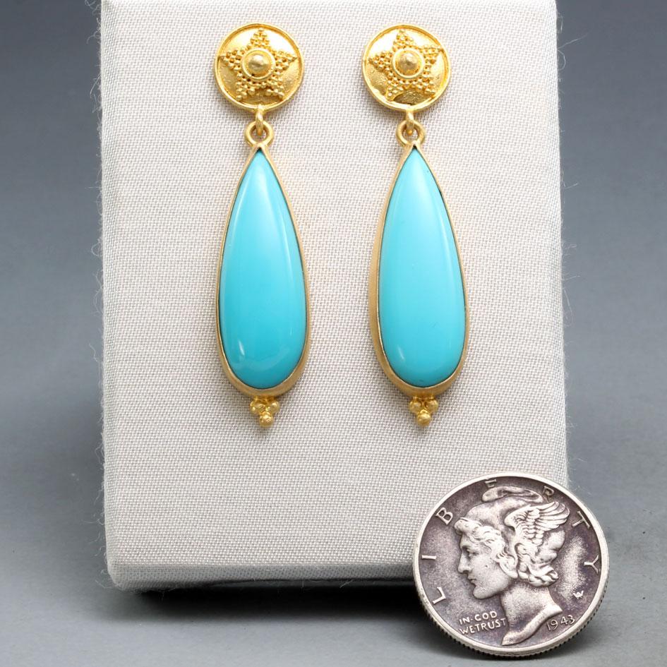 Two flawless 8 x 23 mm pear shaped cabochons of bright Arizona Sleeping Beauty Mine turquoise are set in 18K gold bezels suspended below geometrically granulated artisanally crafted 10 mm posts, with a small matching granulation accent at bottom of