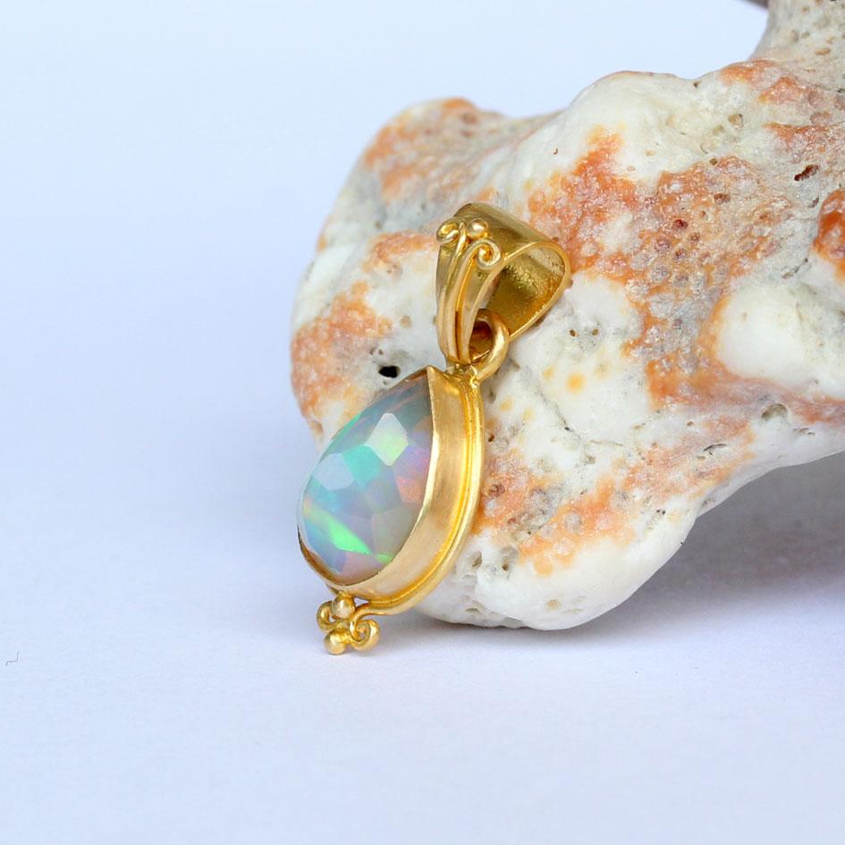 Une opale éthiopienne bleue et verte de 7 x 10 mm en forme de poire facettée est sertie dans une monture artisanale en or 18 carats 