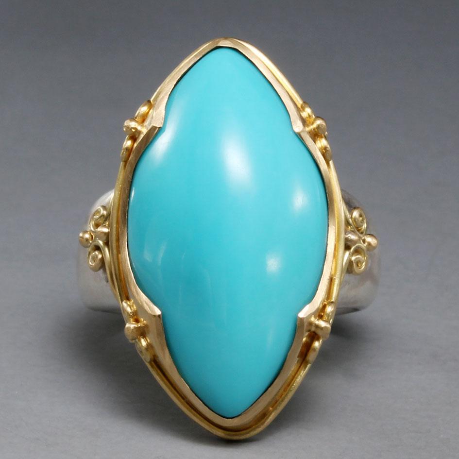 A bright and flawless 14 x 26 mm marquis shaped cabochon of Arizona Sleeping Beauty mine turquoise is held in a medieval-inspired 