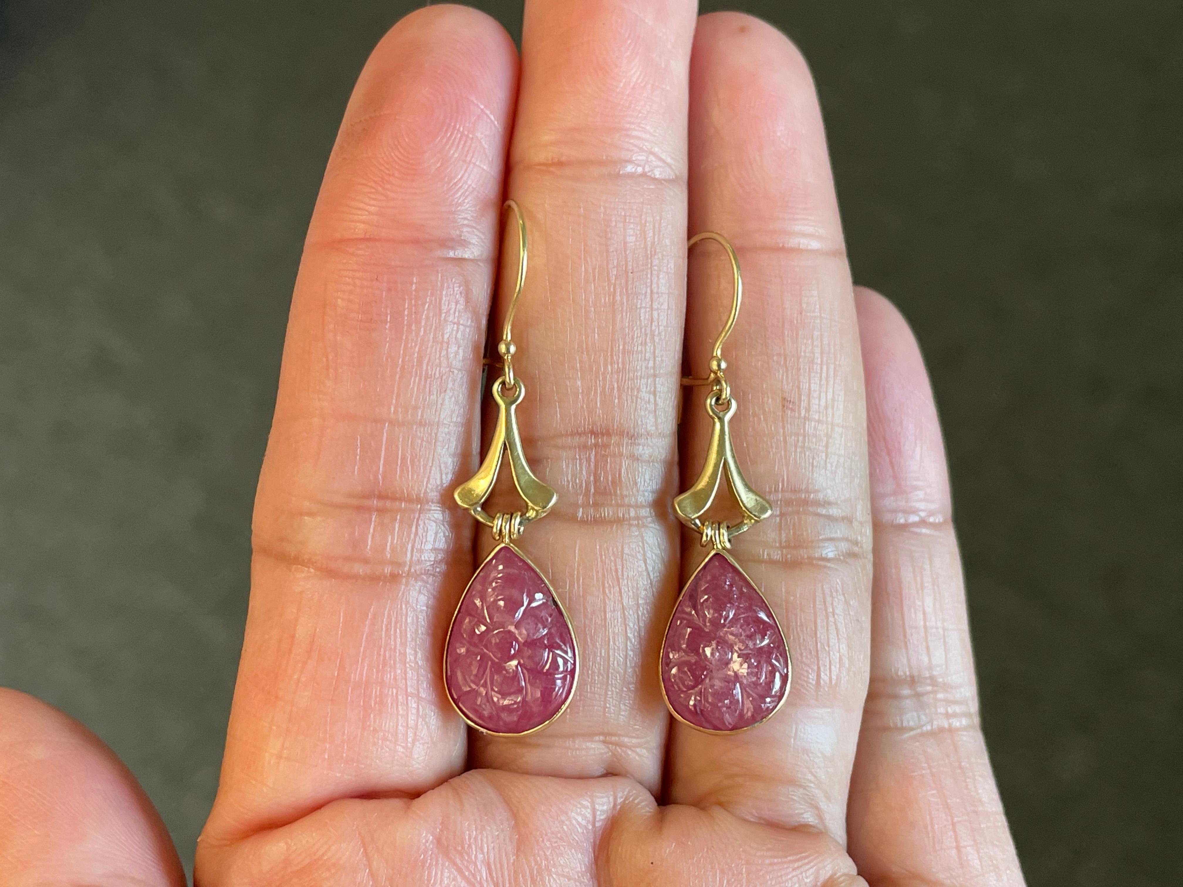 Two flower-pattern, pear shaped carved ruby cabochons approximately 10 x 14 mm dangle below a simple matte finish fluted component and safety clasp wires in this Steven Battelle design.
Simple and elegant.