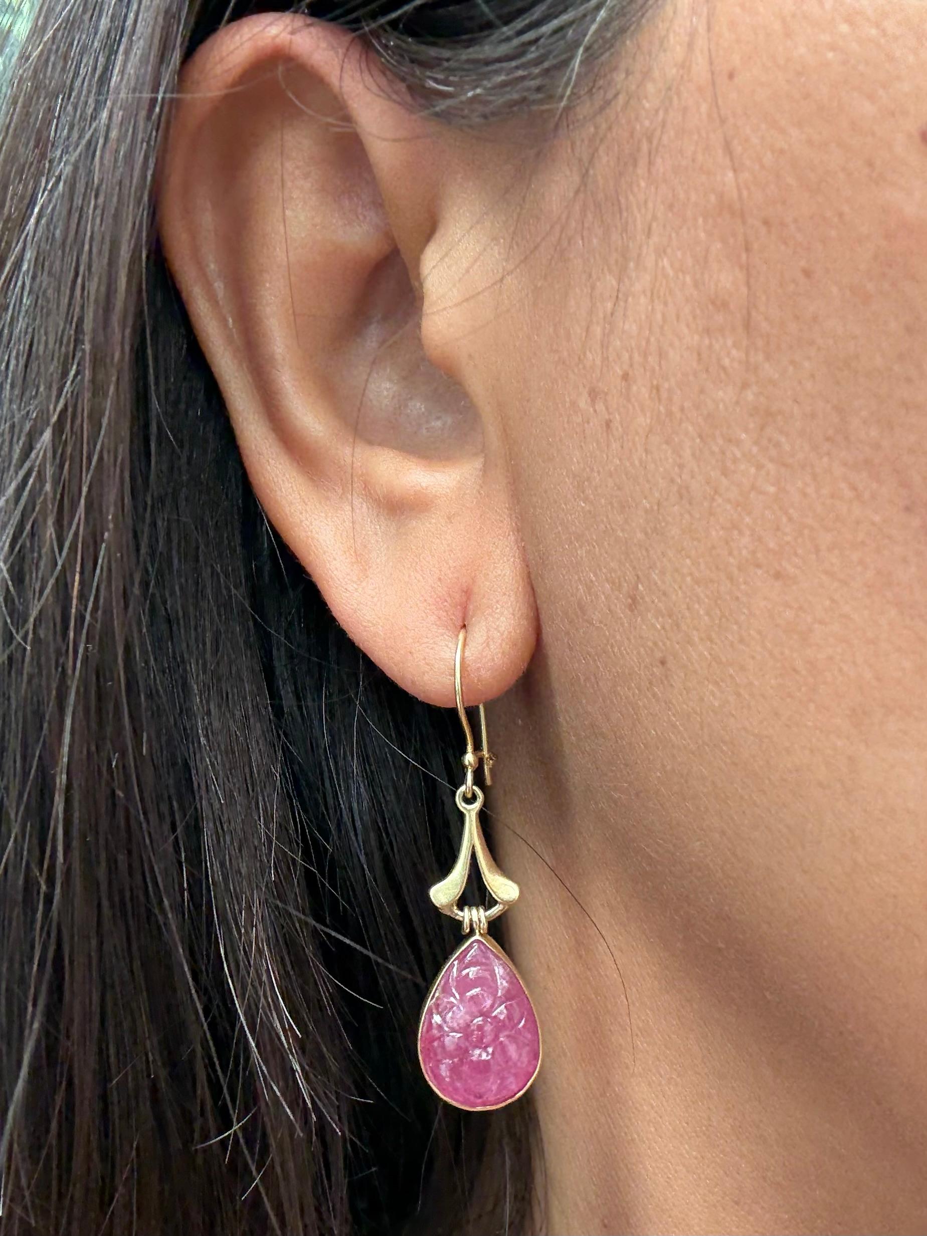 Deux cabochons de rubis sculptés en forme de fleur et de poire d'environ 10 x 14 mm pendent sous un composant cannelé simple à finition mate et des fils de fermoir de sécurité dans ce modèle de Steven Battelle.
Simple et élégant.