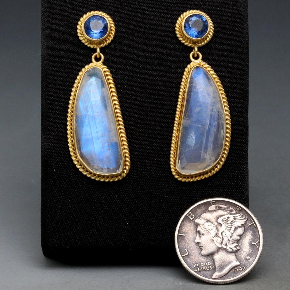 Two 9 x 22 mm shimmering irregular rose-cut faceted rainbow moonstones are surrounded by heavy 18K gold twist wire ornamented settings and dangle below brilliant similarly decorated 5 mm faceted Kyanite posts in this design.  Complementary flashing