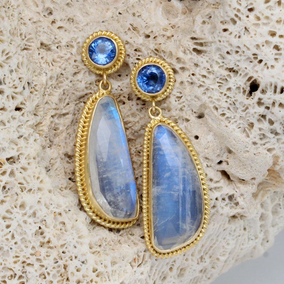 Two 9 x 22 mm shimmering irregular rose-cut faceted rainbow moonstones are surrounded by heavy 18K gold twist wire ornamented settings and dangle below brilliant similarly decorated 5 mm faceted Kyanite posts in this design.  Complementary flashing